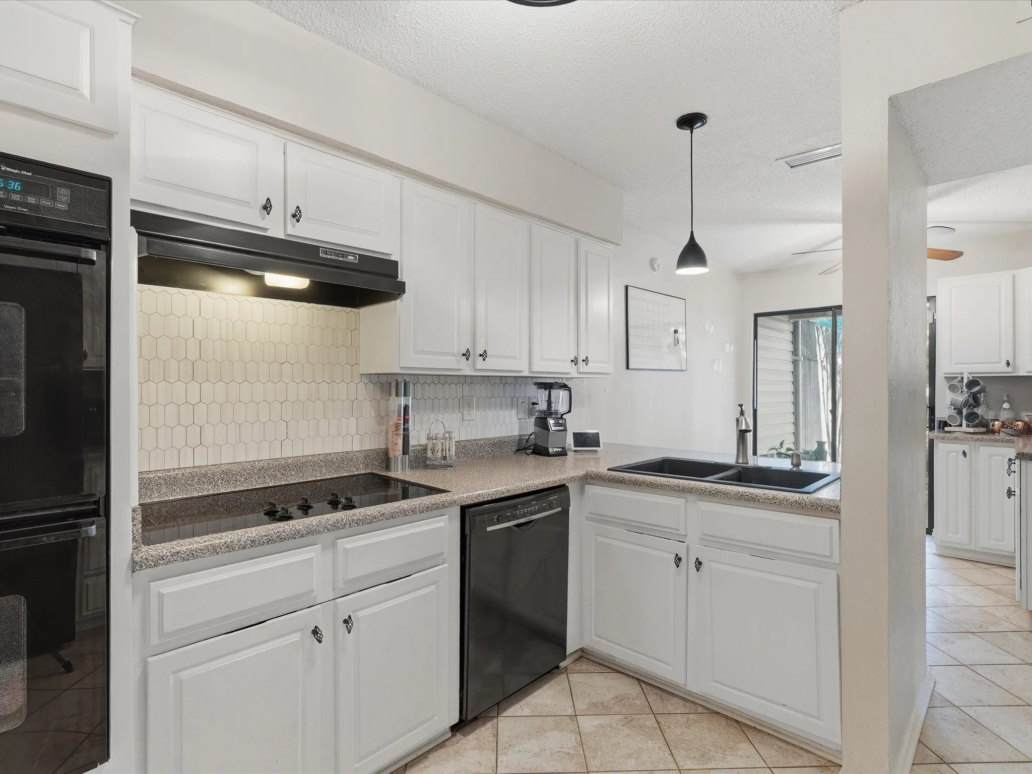 Kitchen featuring white cabinetry, a black built-in oven, black cooktop, black dishwasher, and a black double-basin sink