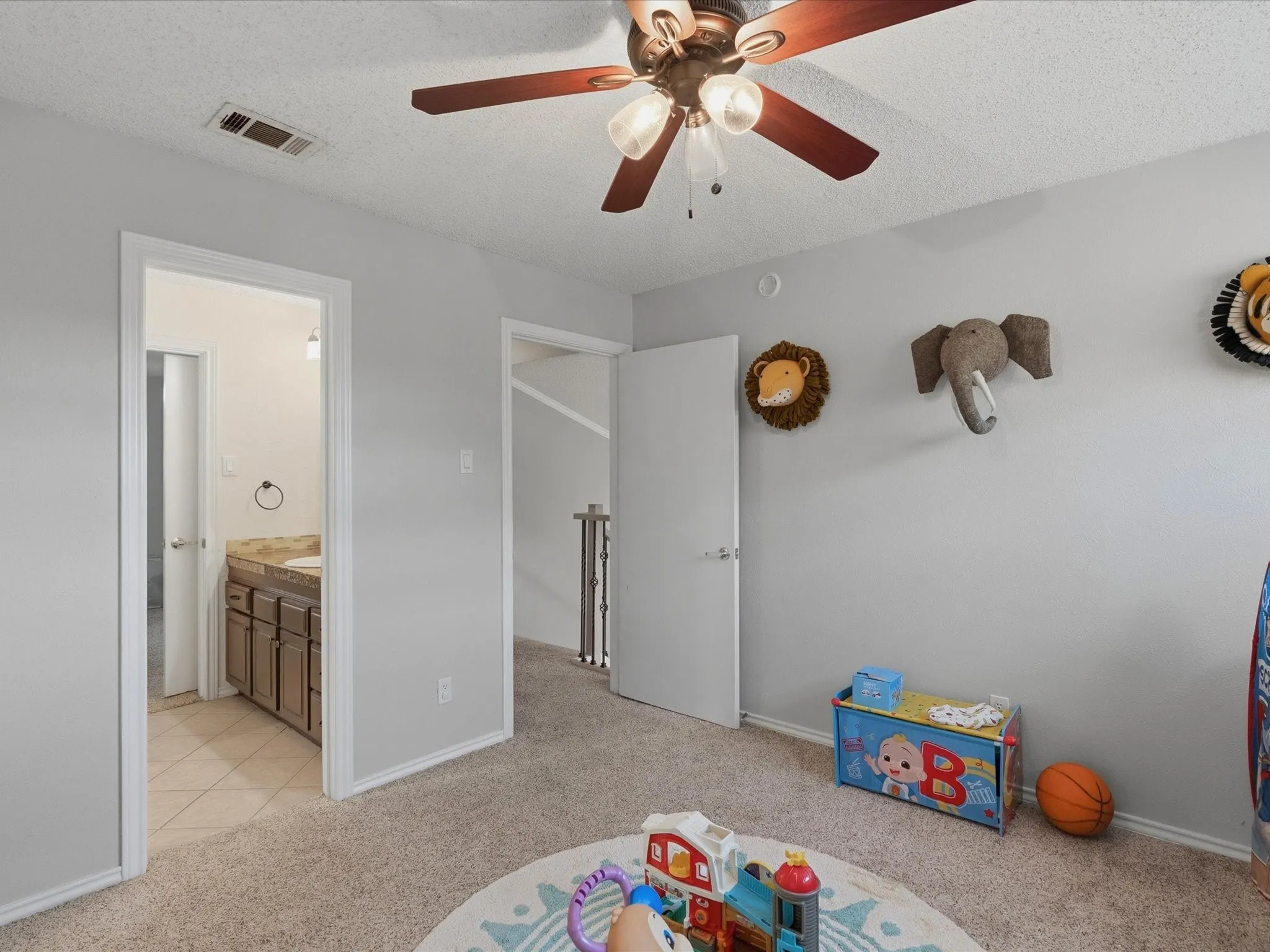 Carpeted room with light gray walls, a ceiling fan with wood-finish blades, and white​​‌​​​​‌​​‌‌​‌‌​​​‌‌​‌​‌​‌​​​‌​​ trim