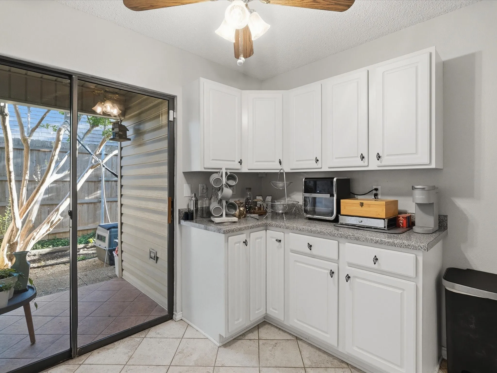 White shaker-style cabinetry with dark hardware and a speckled countertop