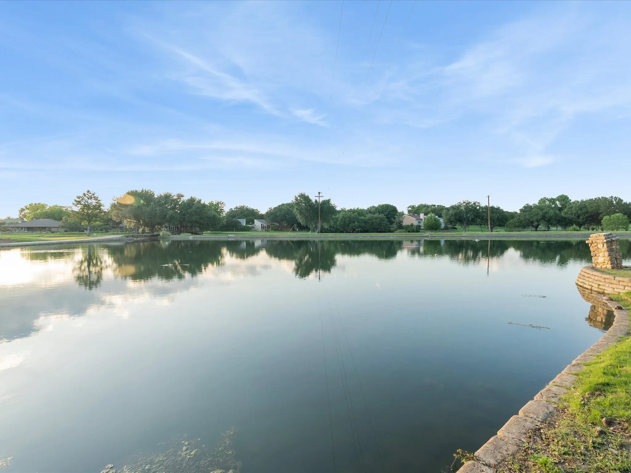 Expansive water feature with a stone-lined bank and a stone pillar