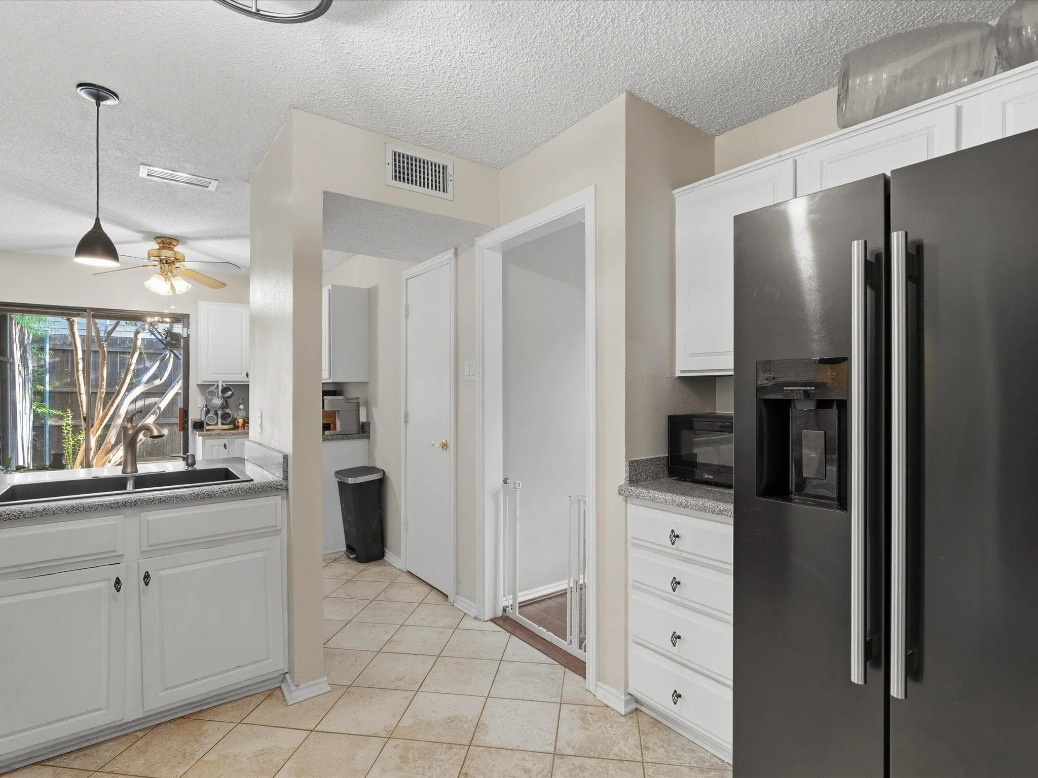 Kitchen featuring white cabinetry, light-toned tiled flooring, and dark-finish appliances
