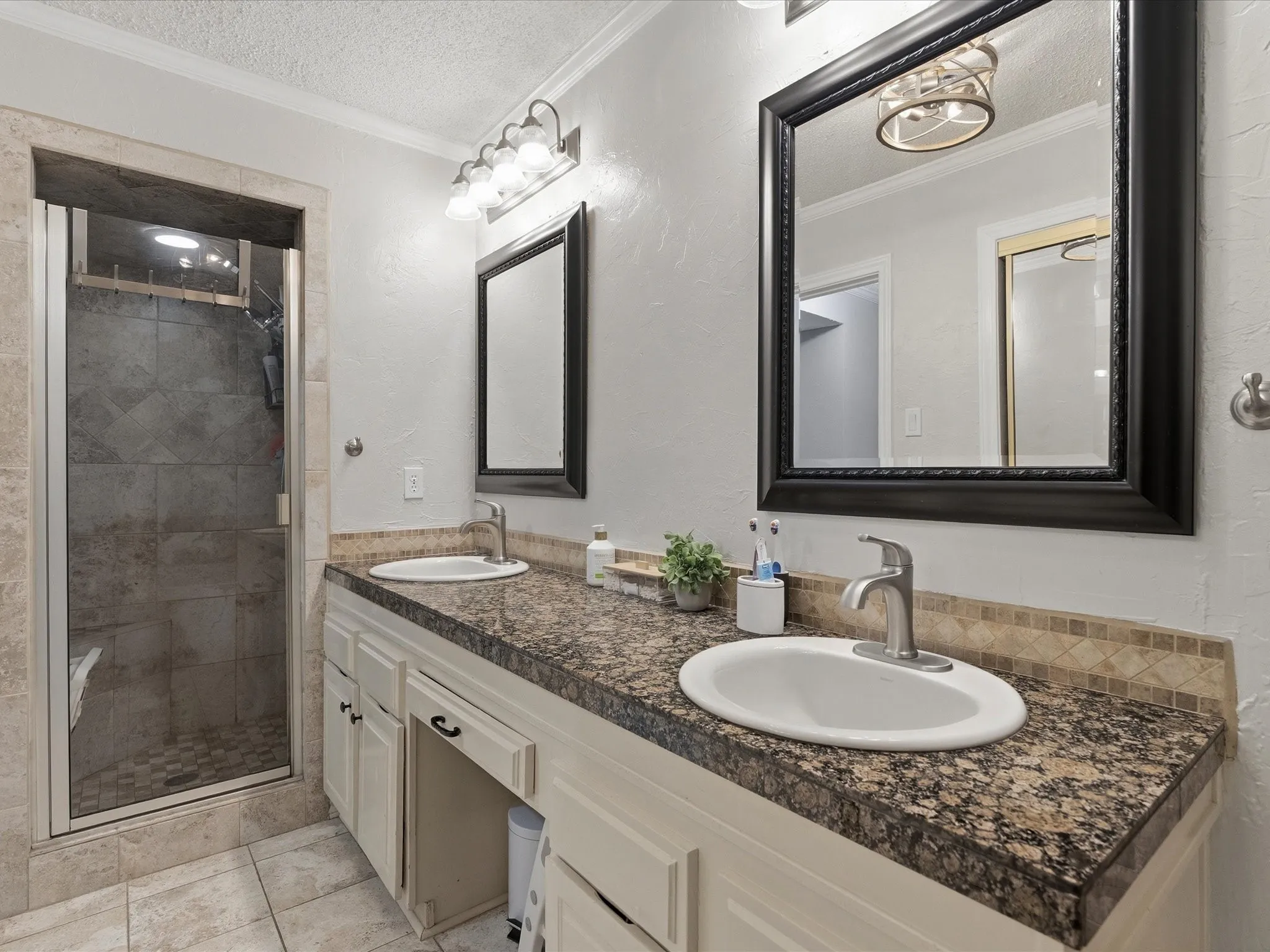 Dual vanity with granite-style countertops, under-mount sinks, and a mosaic tile backsplash