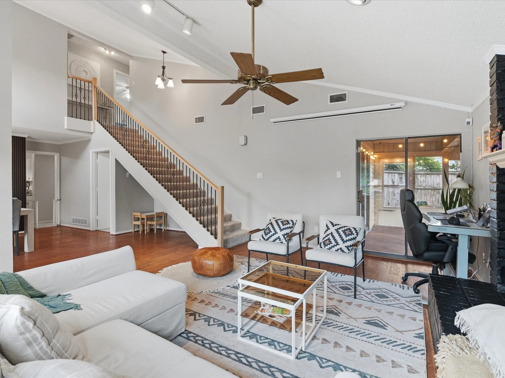 Spacious living area featuring vaulted ceilings, wood-finish flooring, and a multi-level staircase with carpeted treads and metal balusters