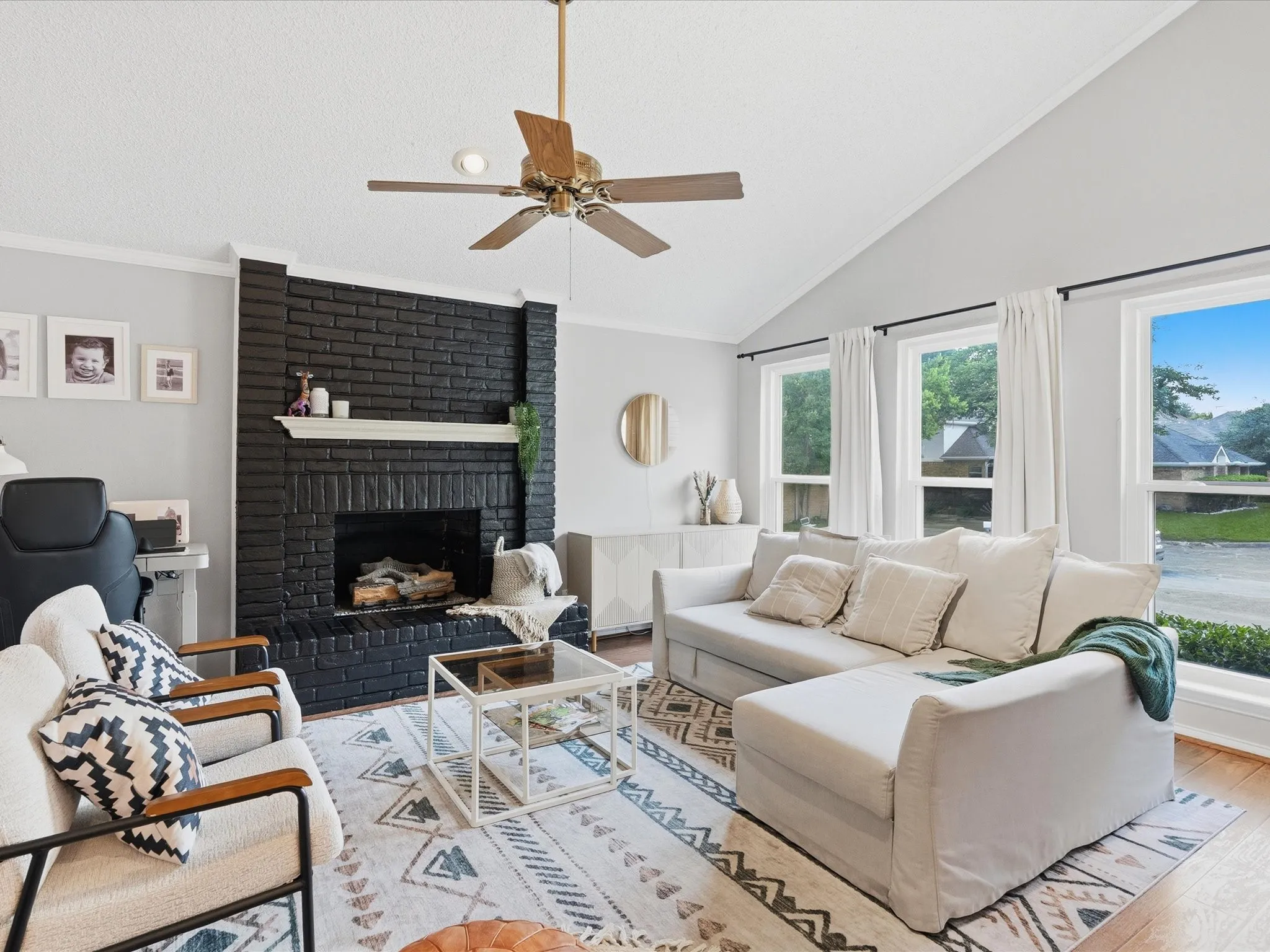 Living area featuring a black brick fireplace with a white mantel, vaulted ceilings, and wood-finish flooring