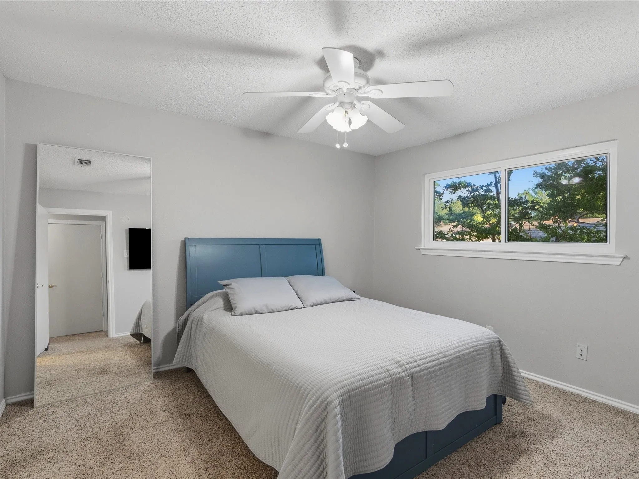 Room featuring light-colored walls, carpet flooring, a ceiling fan with integrated lighting, and a window with white trim