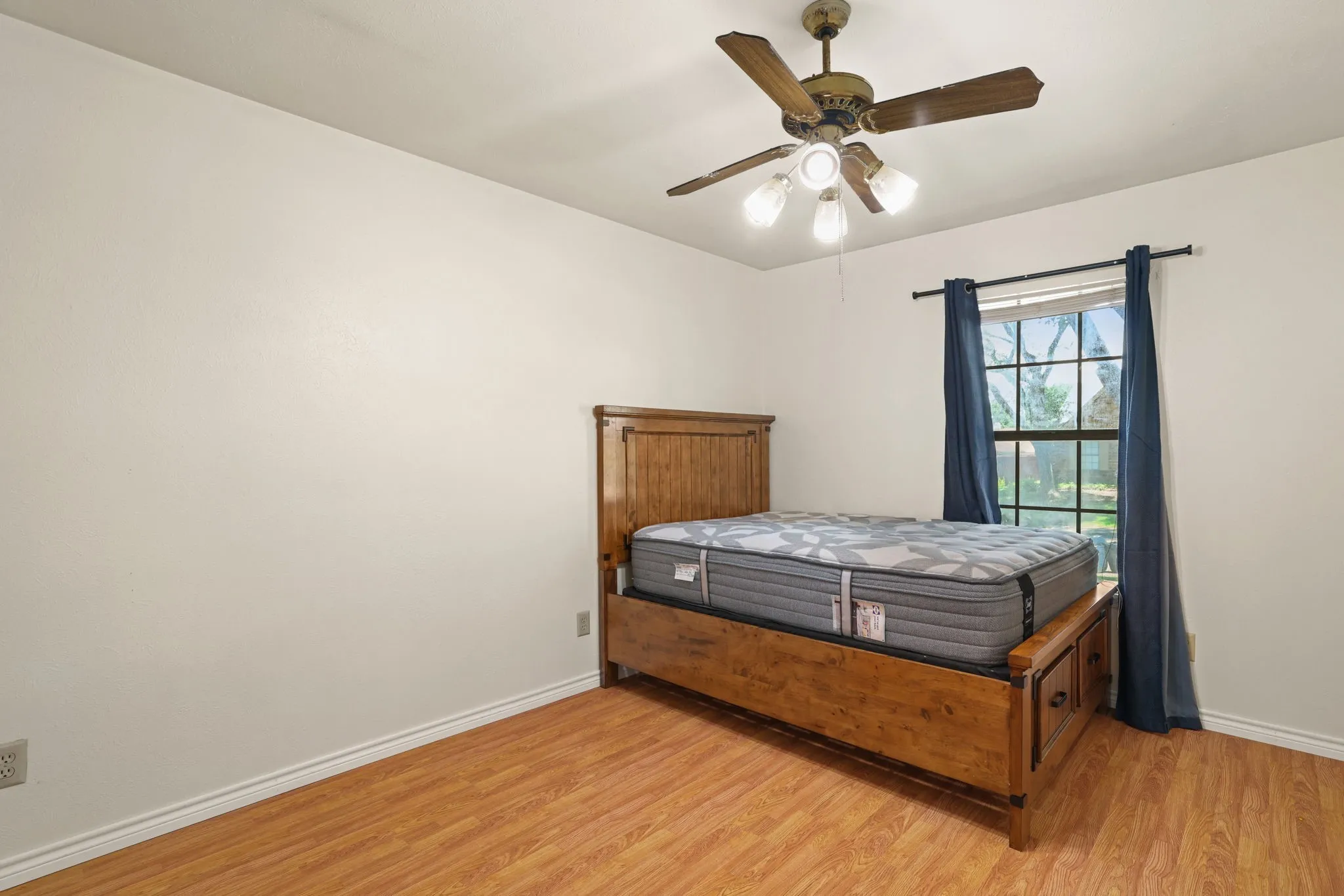 Interior room featuring wood-finish flooring, a ceiling fan with integrated lighting, and a window with natural light