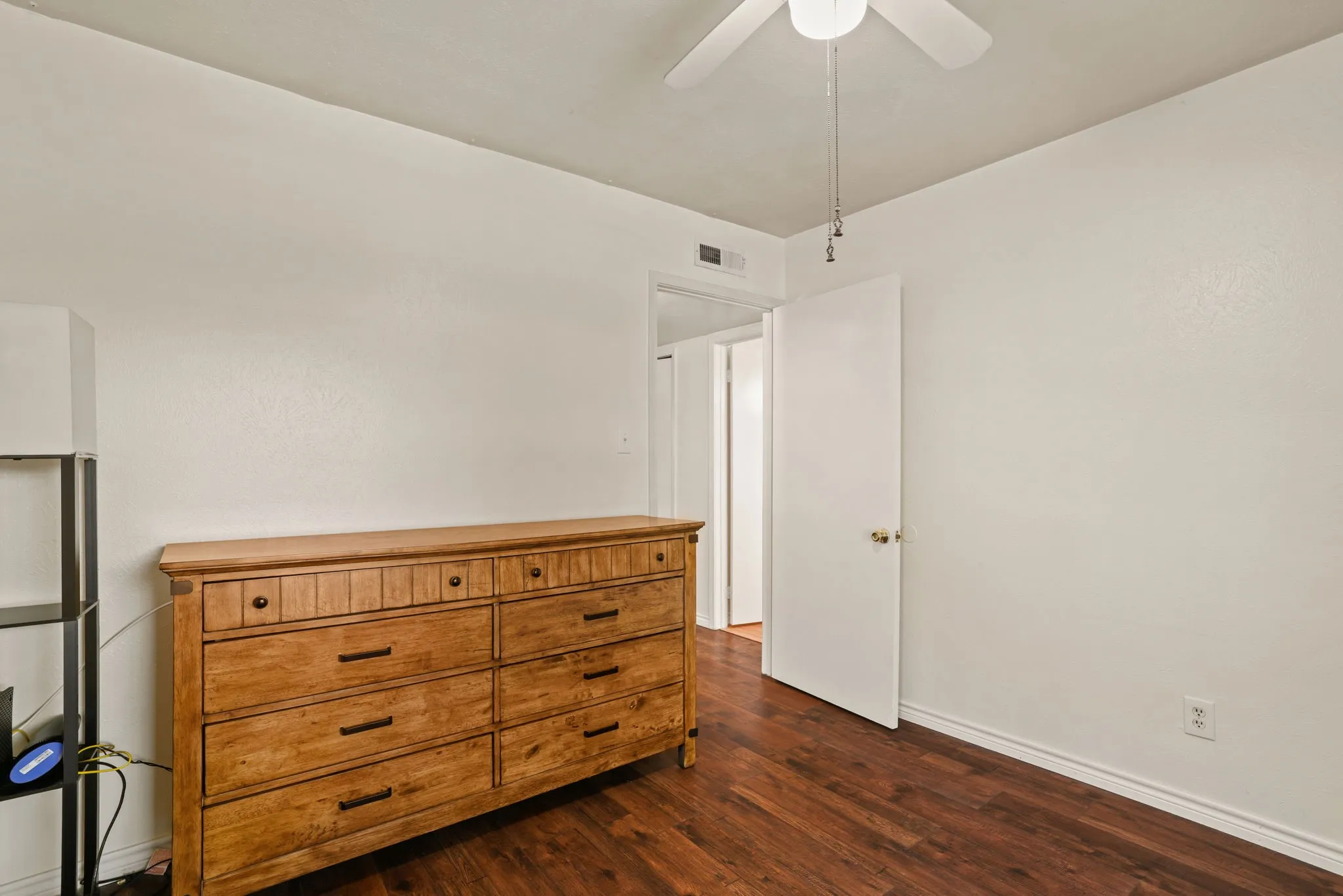 Room featuring wood-finish flooring, white painted walls, and a ceiling fan
