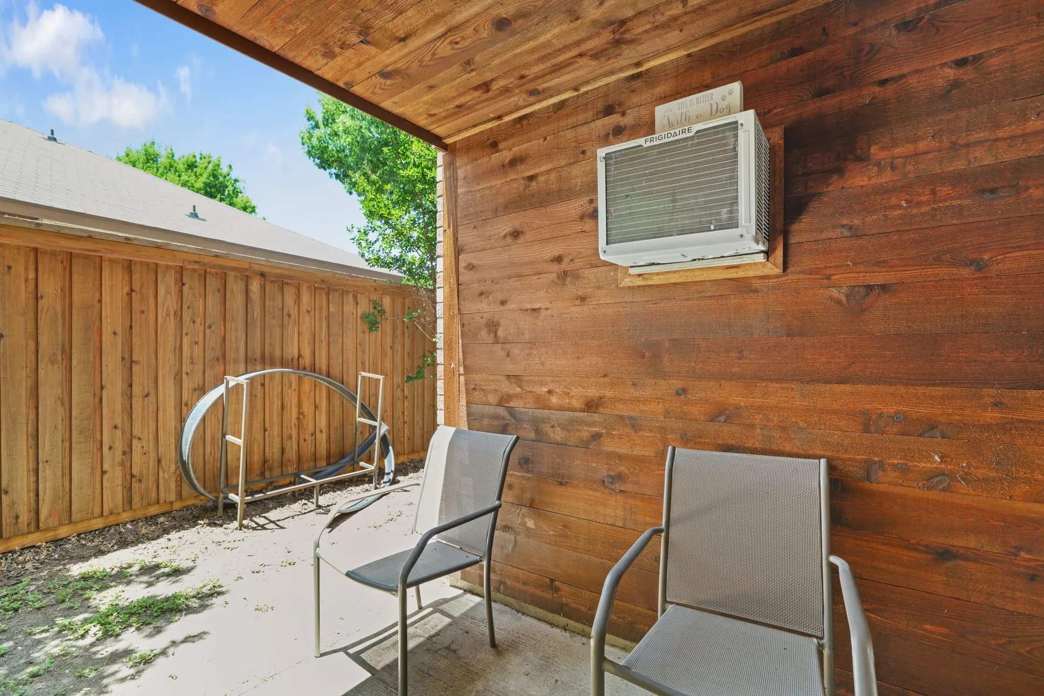 Covered outdoor patio area featuring a stained wood plank ceiling and wall