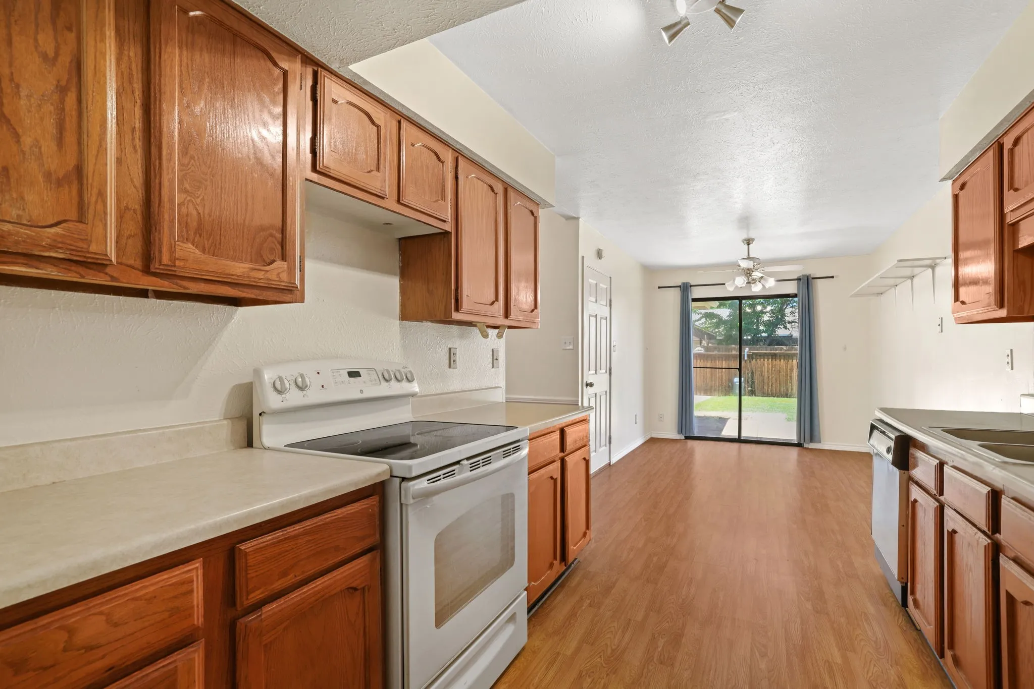 Kitchen featuring wood cabinetry, light-toned countertops, and a white electric range