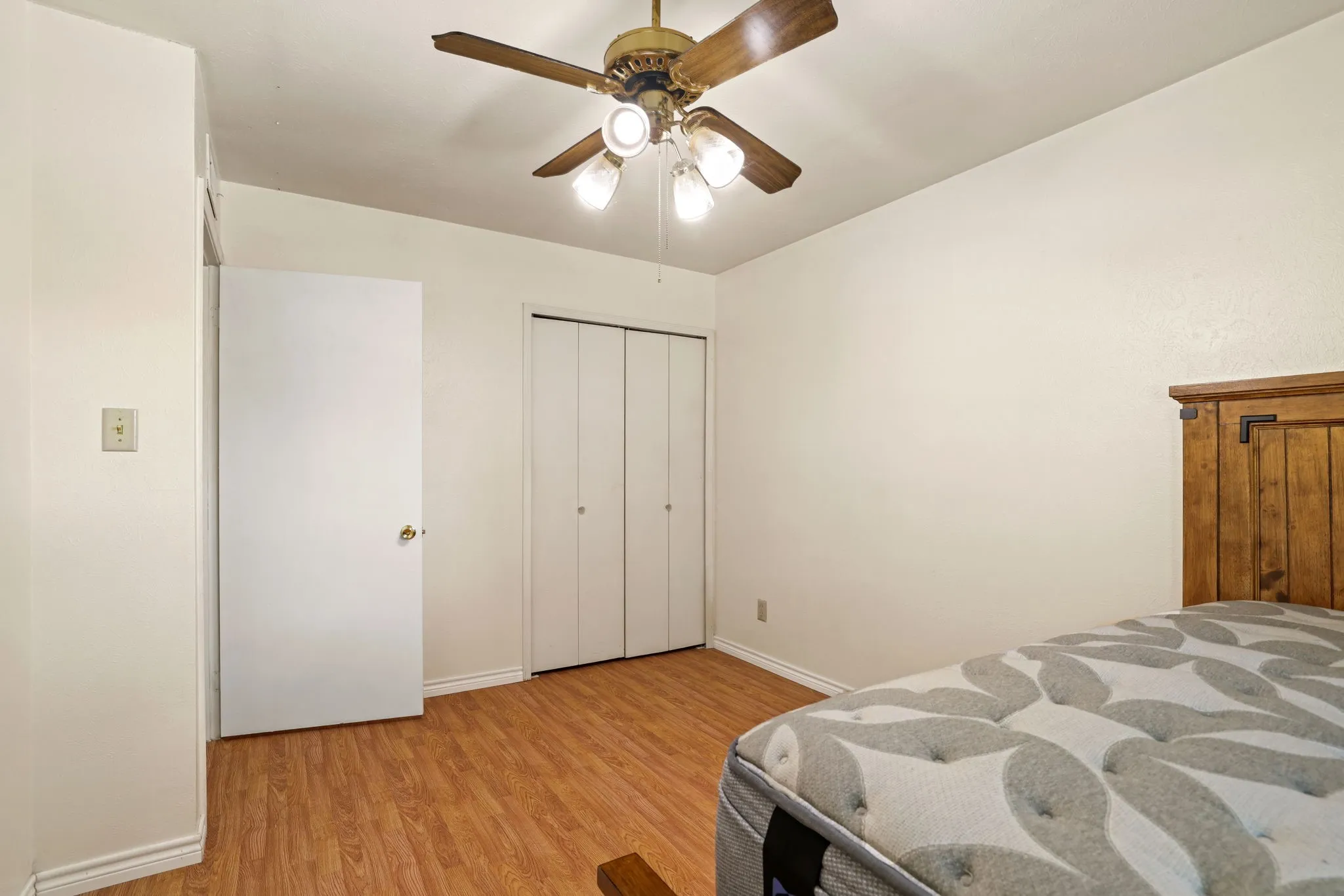 Room featuring wood-finish flooring, a ceiling fan with integrated lighting, and a closet with bifold doors