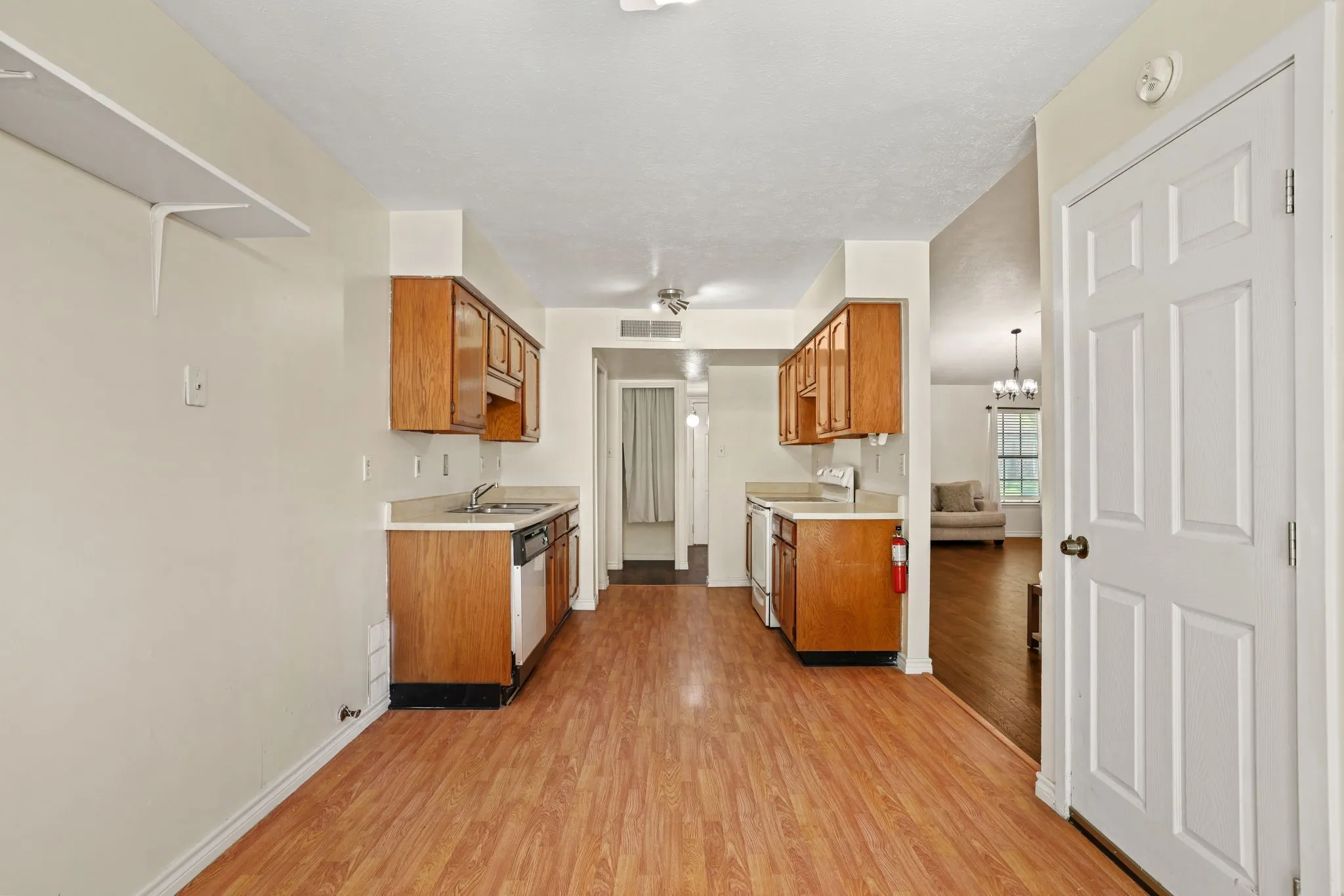 Kitchen featuring wood-finish flooring, wood cabinetry, laminate countertops, and a built-in dishwasher