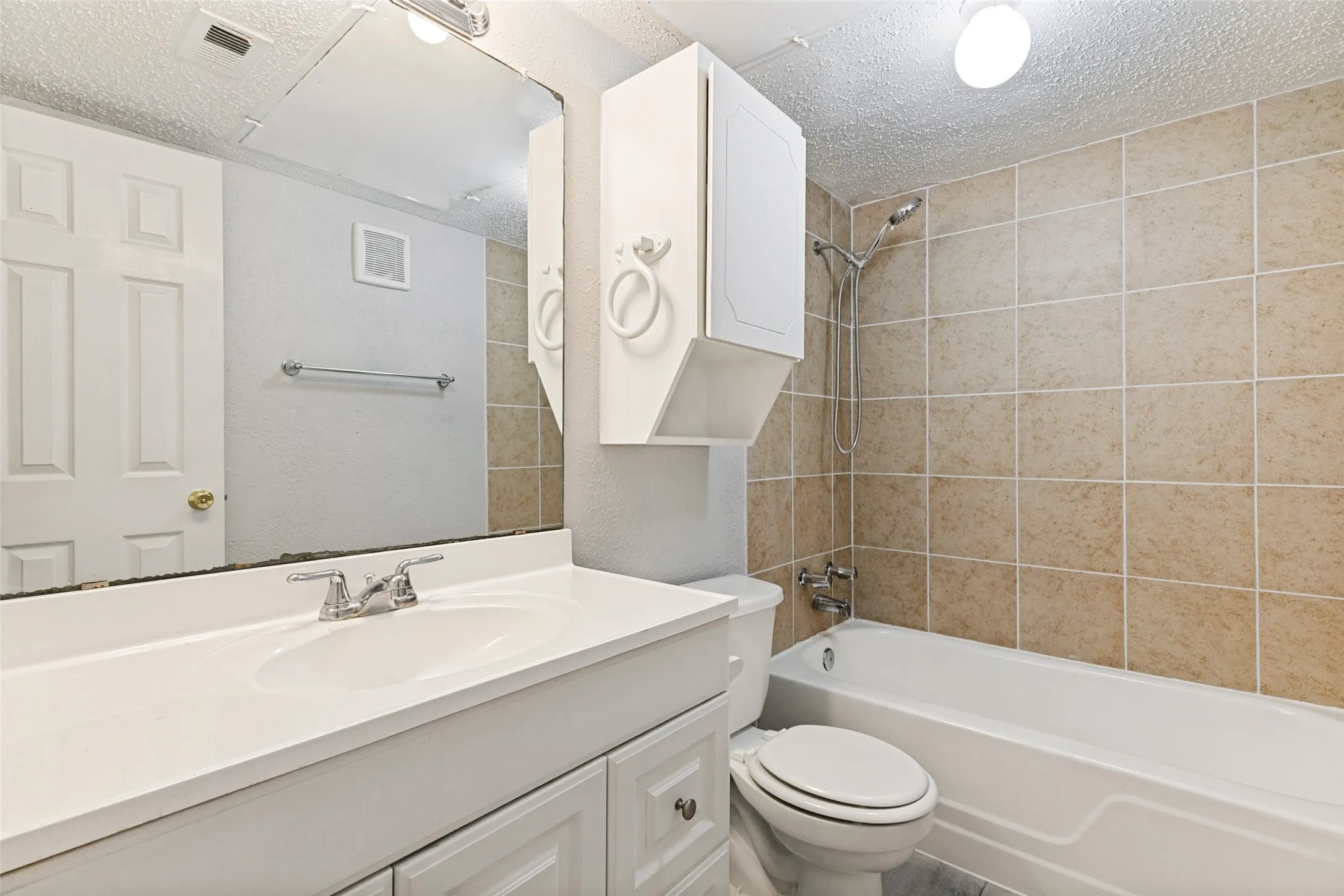 Bathroom featuring a white vanity with integrated sink, chrome faucet, and a large wall mirror