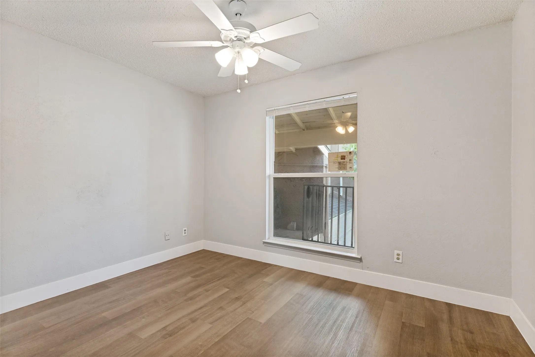 Room featuring wood-finish flooring, white baseboards, a ceiling fan with integrated lighting, and a single window