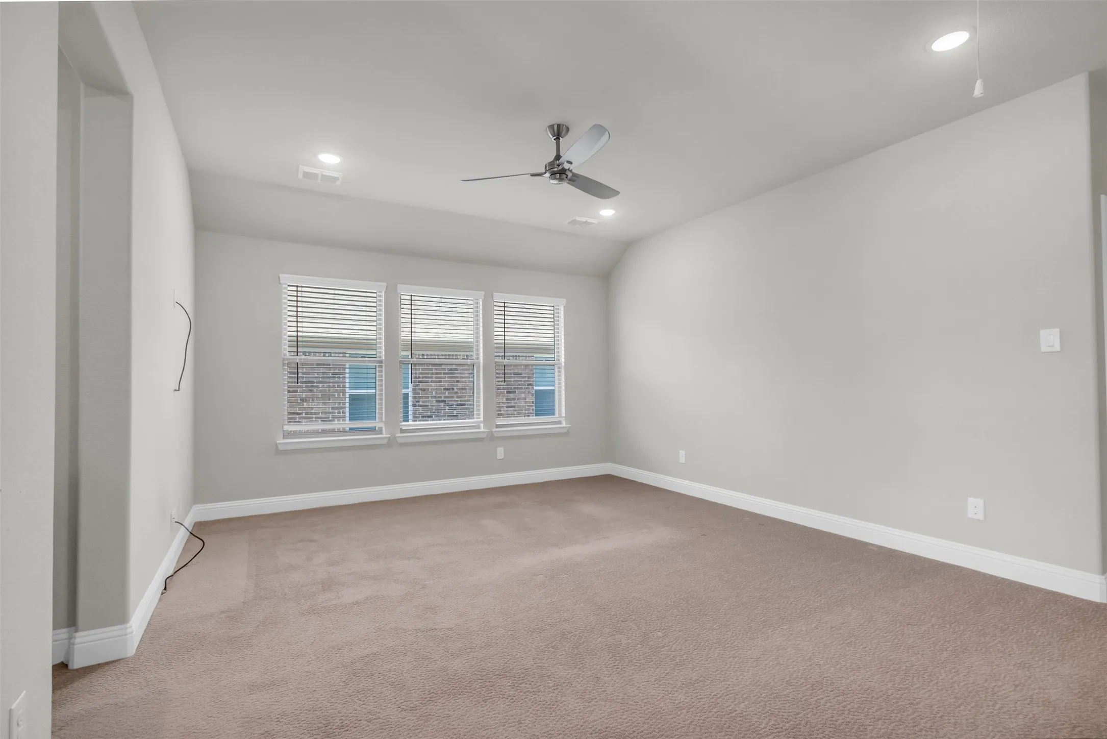 Carpeted empty room with lofted ceiling and ceiling fan