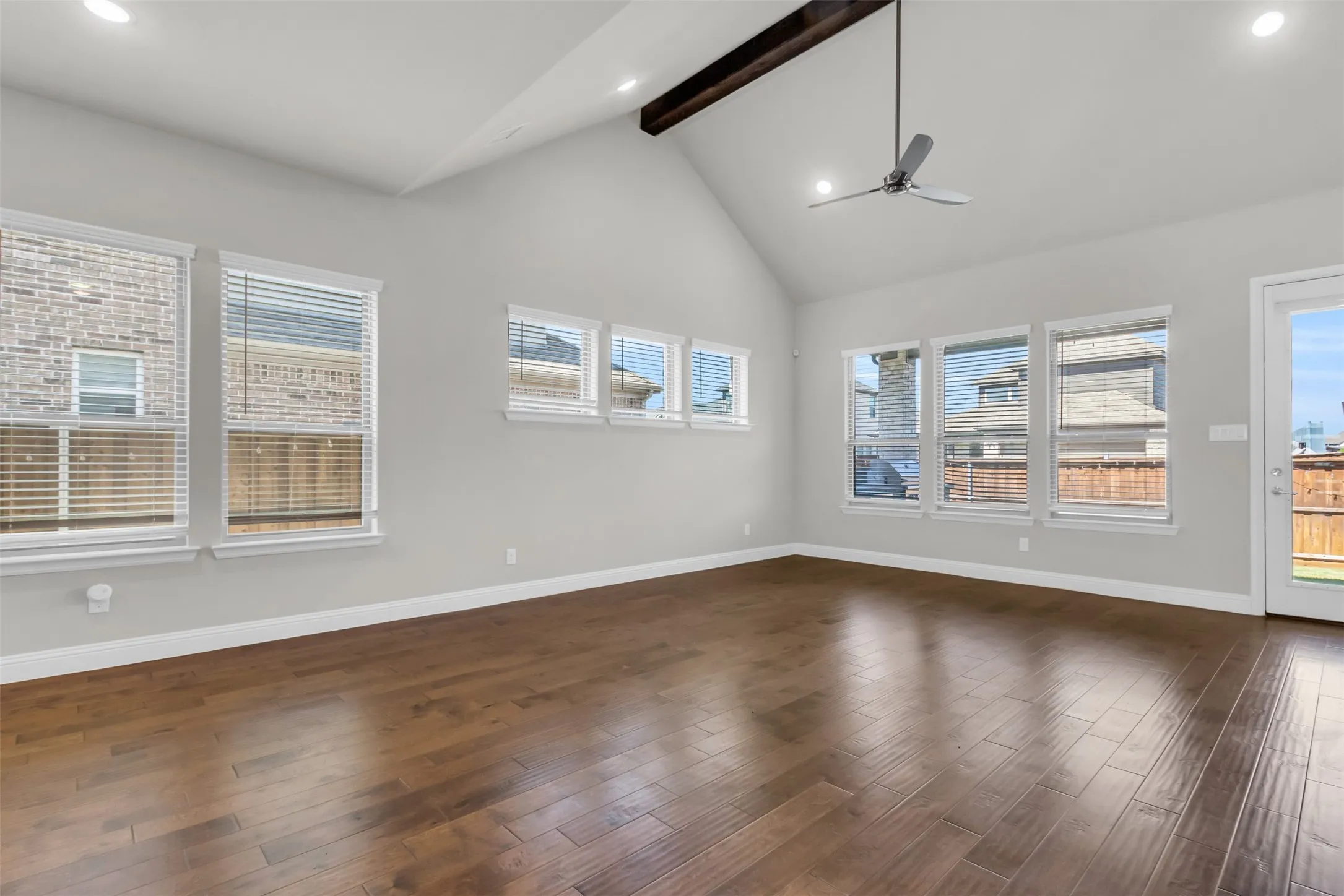 Unfurnished living room with beamed ceiling, dark hardwood / wood-style flooring, ceiling fan, and high vaulted ceiling