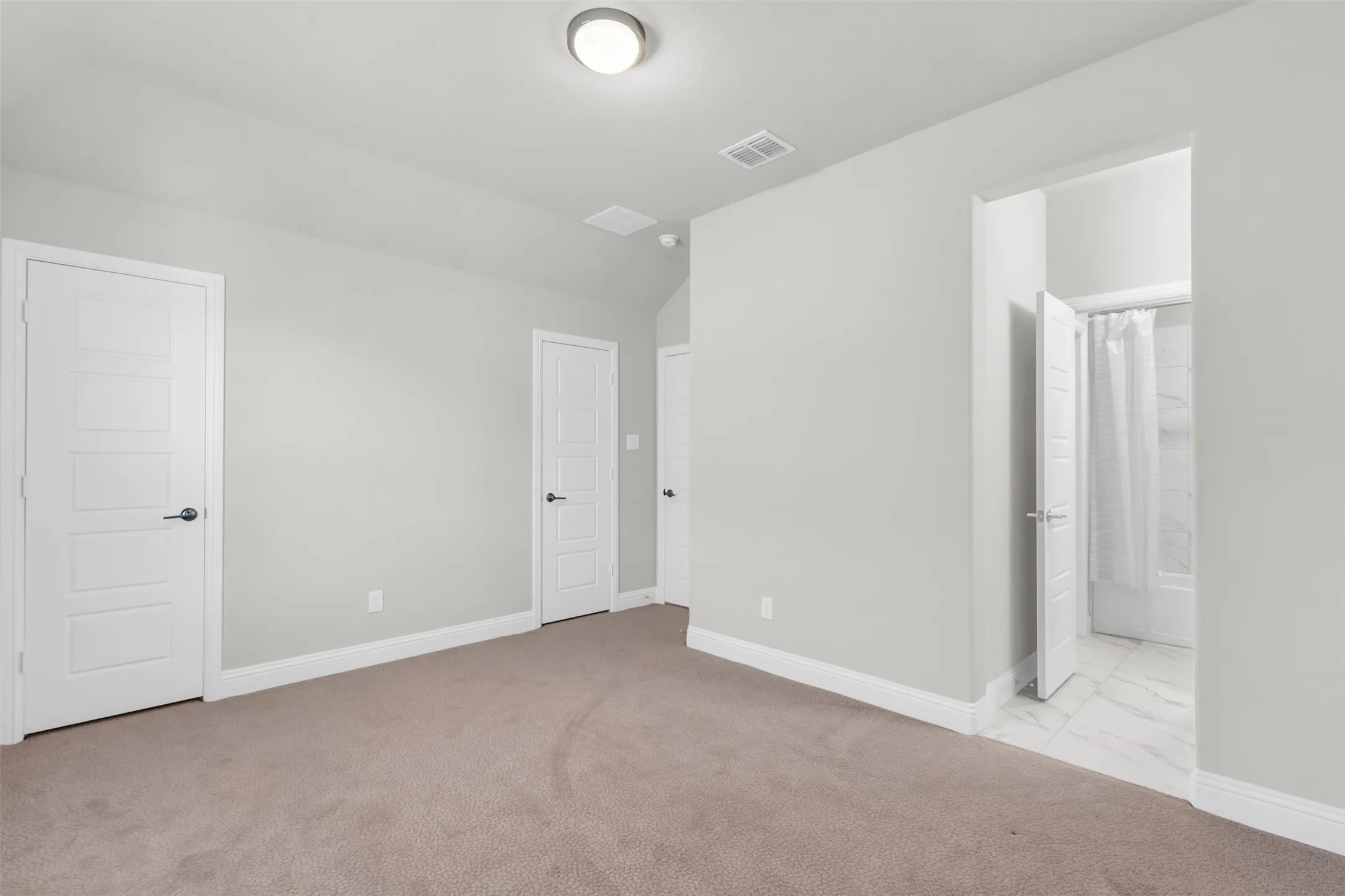 Unfurnished bedroom featuring connected bathroom and light colored carpet