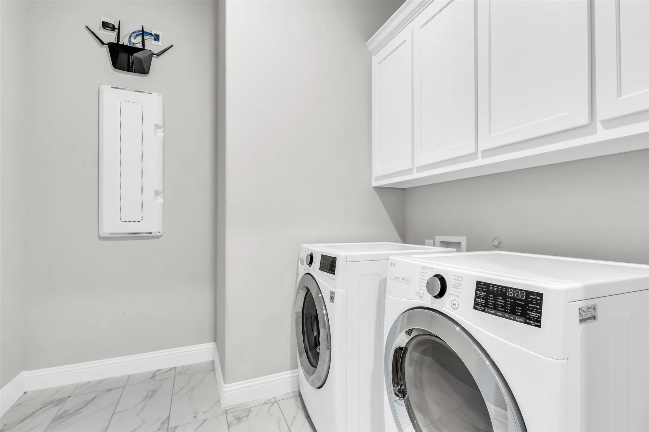 Washroom featuring cabinets, independent washer and dryer, and light tile patterned floors