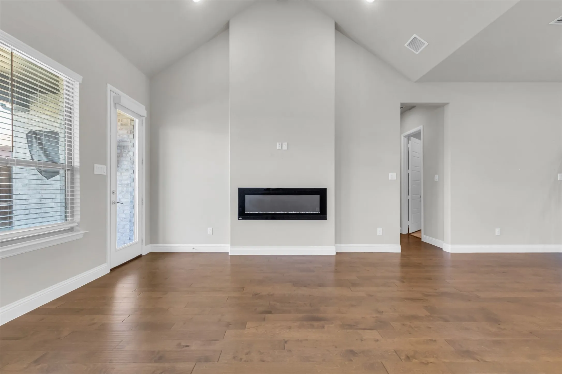 Unfurnished living room with high vaulted ceiling and hardwood / wood-style floors