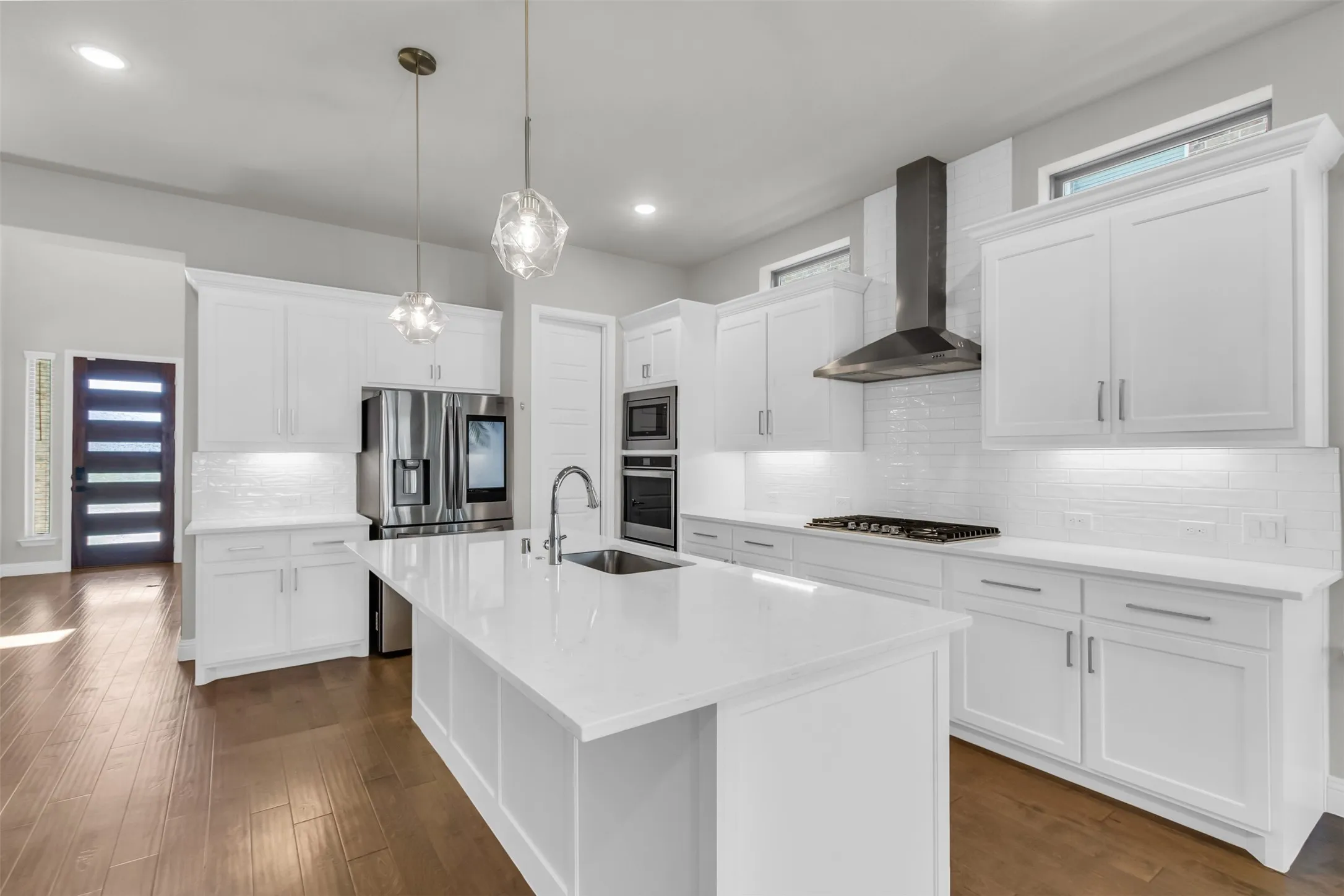 Kitchen with tasteful backsplash, an island with sink, wall chimney exhaust hood, dark hardwood / wood-style floors, and appliances with stainless steel finishes