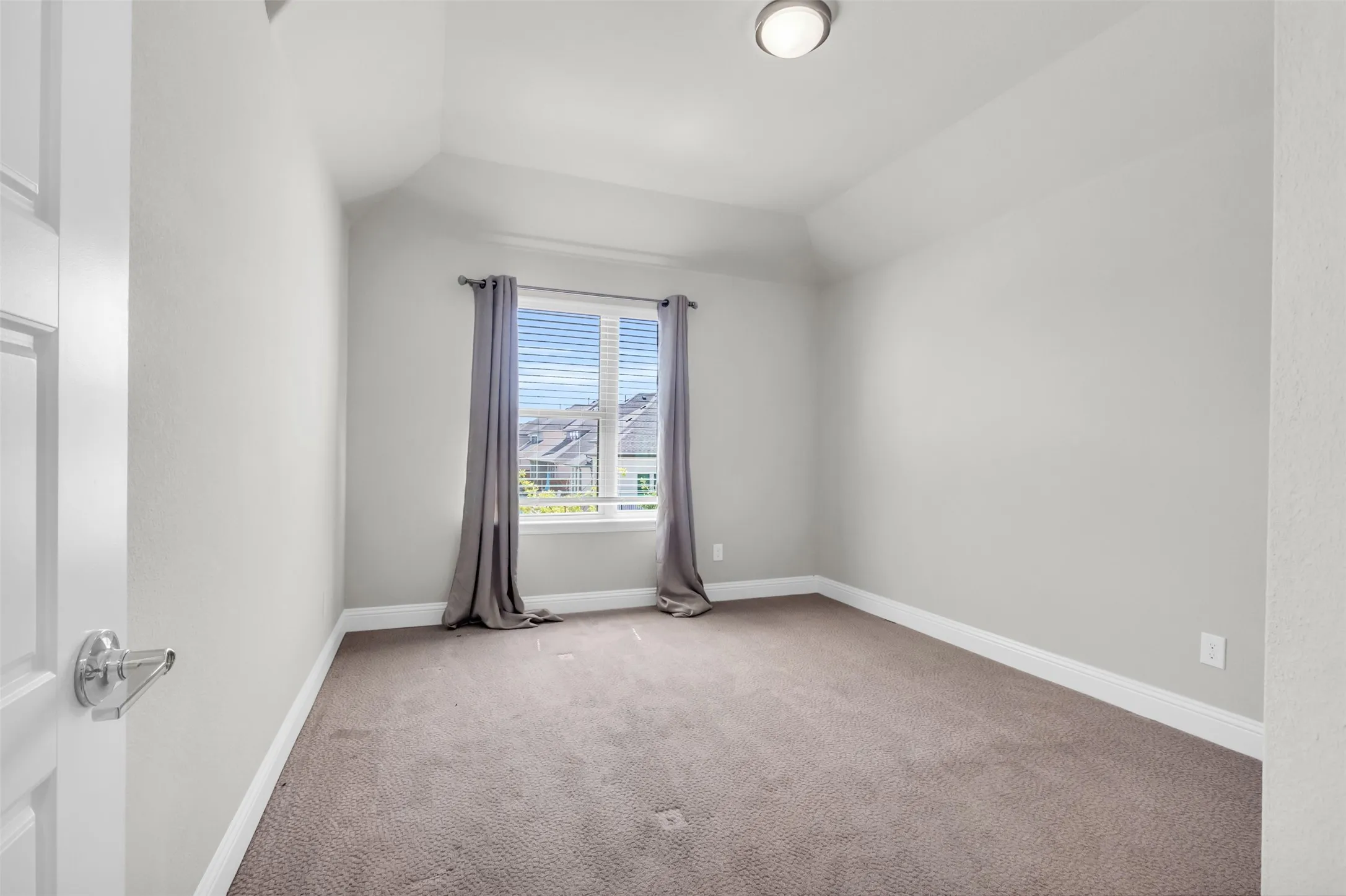 Spare room with carpet and vaulted ceiling