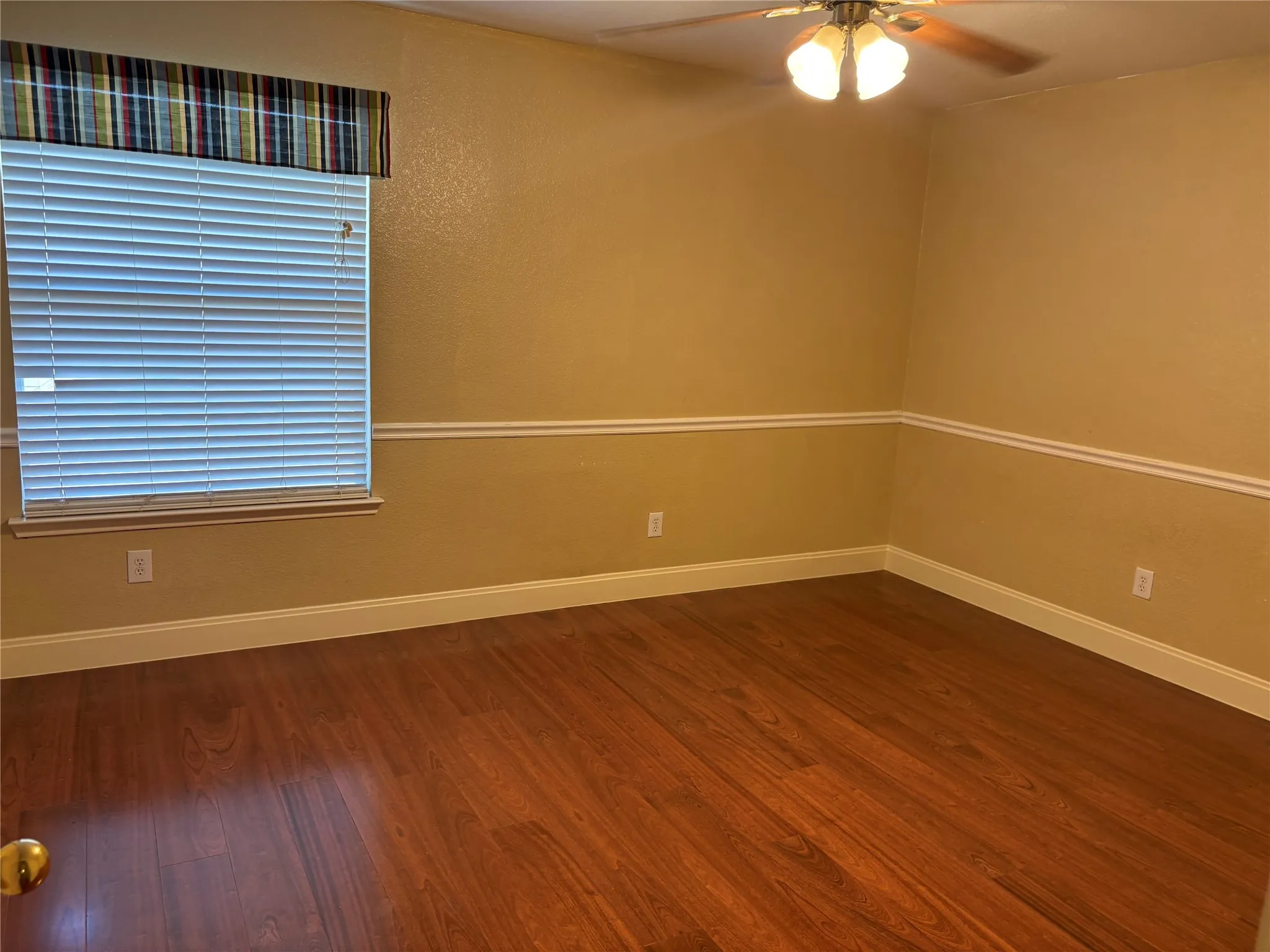 Room featuring wood-finish flooring, a window with horizontal blinds, and a ceiling fan with integrated lighting