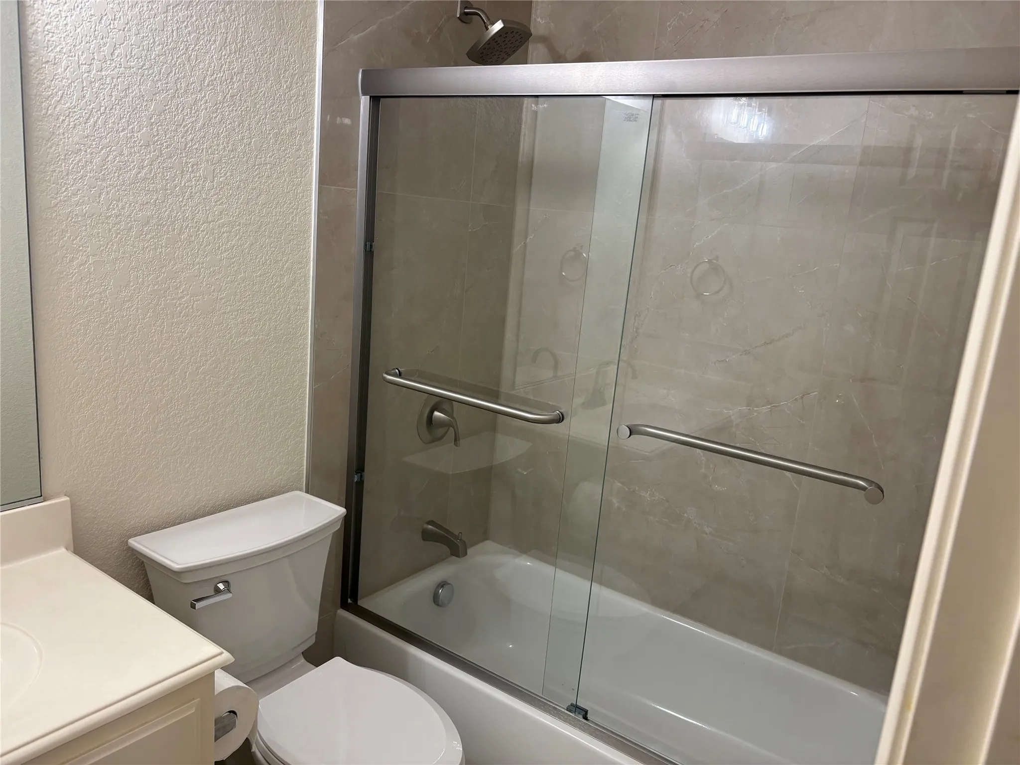 Full bathroom featuring a tub-shower combination with sliding glass doors and brushed nickel hardware