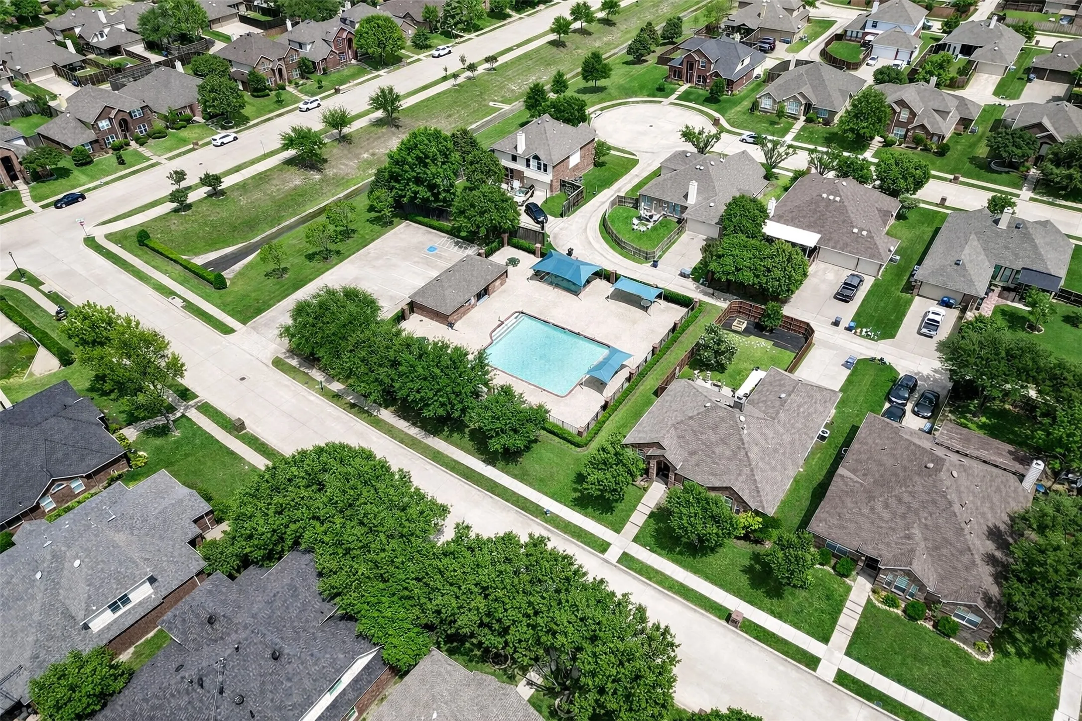 Aerial perspective showcasing a residential community with numerous single-family homes, manicured lawns, and mature trees