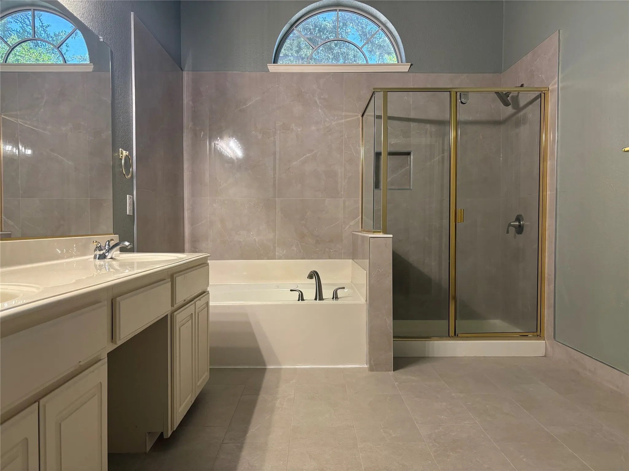 Spacious bathroom featuring a dual vanity, separate built-in bathtub, and a glass-enclosed shower