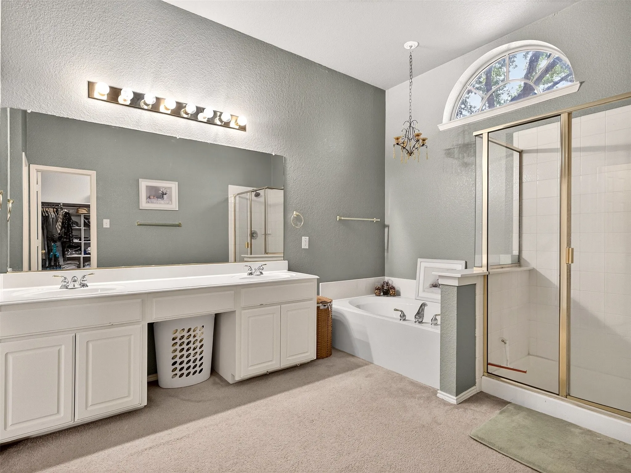 Spacious bathroom featuring a dual vanity with white cabinetry and an expansive mirror