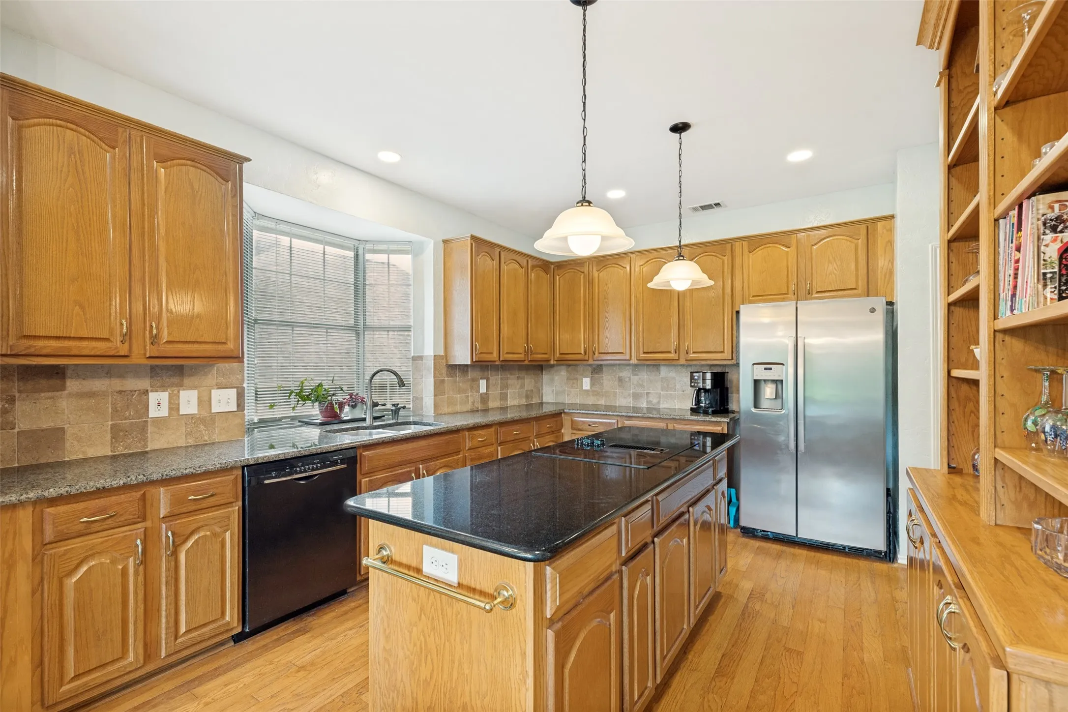 The large gourmet kitchen has granite counters, center island, and pendant lights over the electric cooktop which is perfect for entertaining.