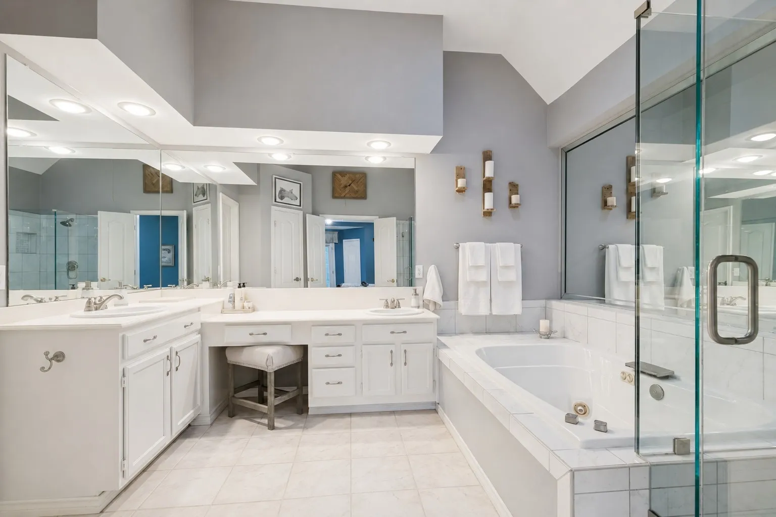 The roomy, remodeled primary bathroom has a tall ceiling, and 2 sinks...