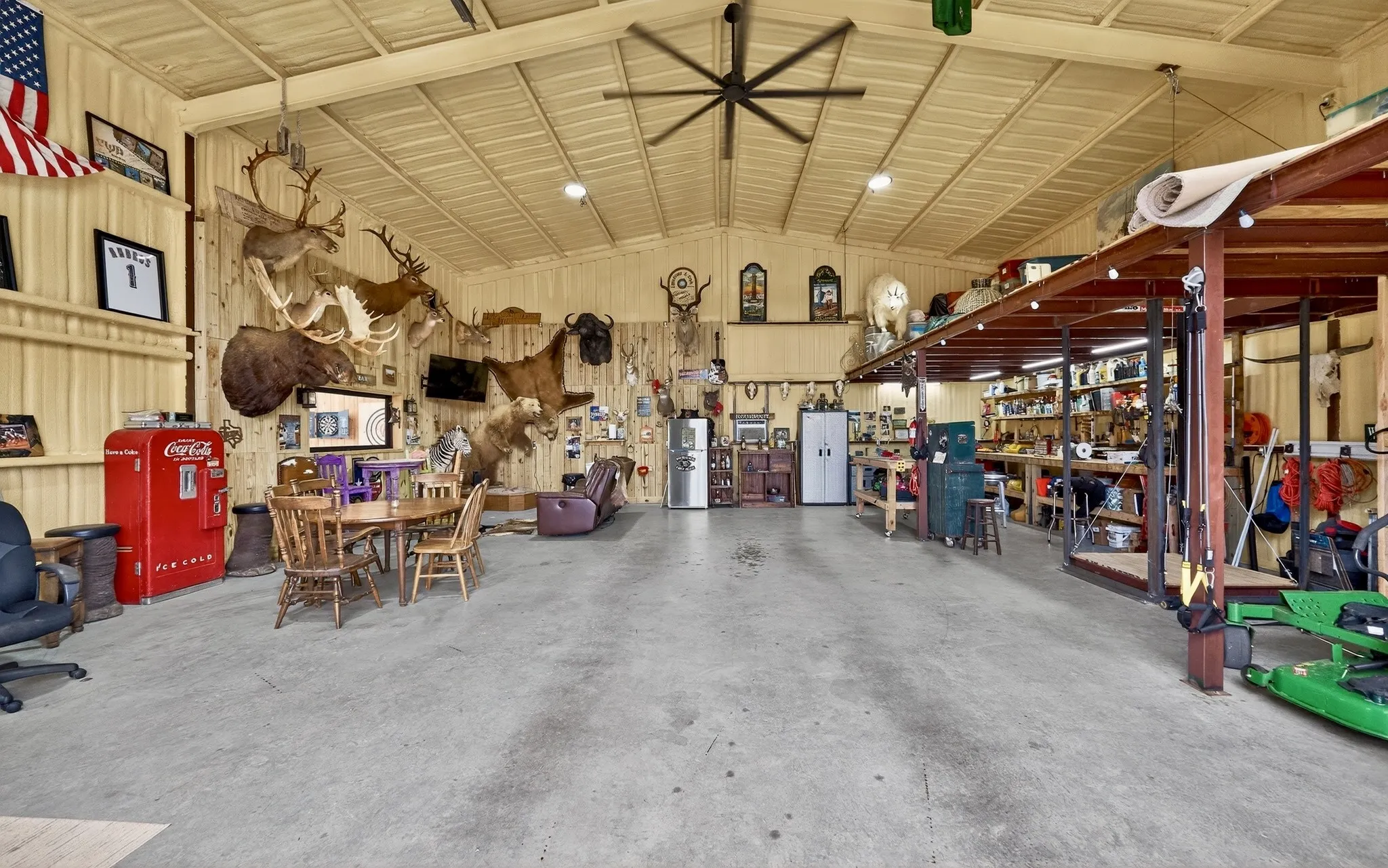 Spacious utility building featuring a concrete floor, high ceilings with exposed beams, and a large ceiling fan