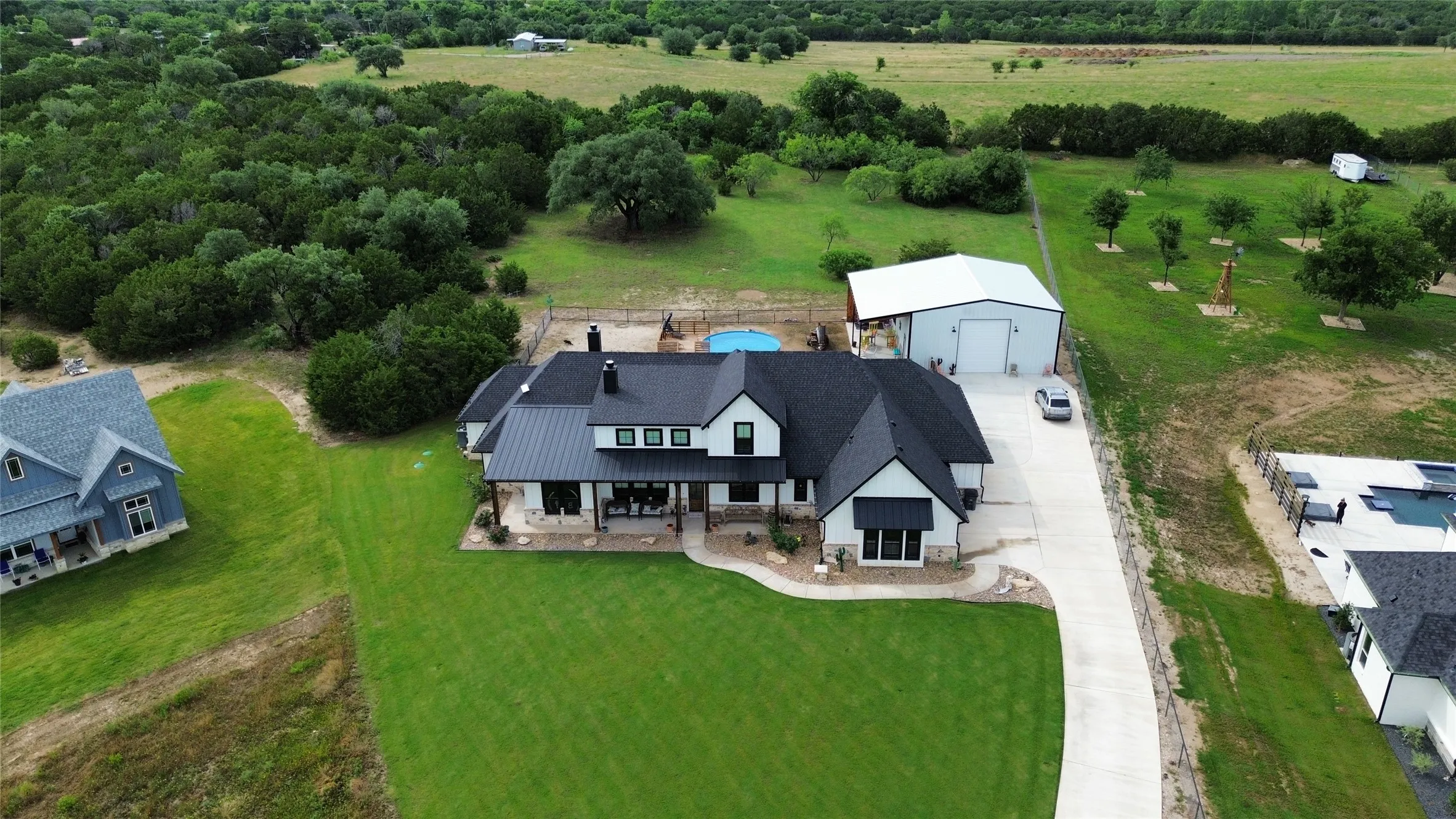 Modern farmhouse exterior featuring a black metal roof, white siding, and black awnings