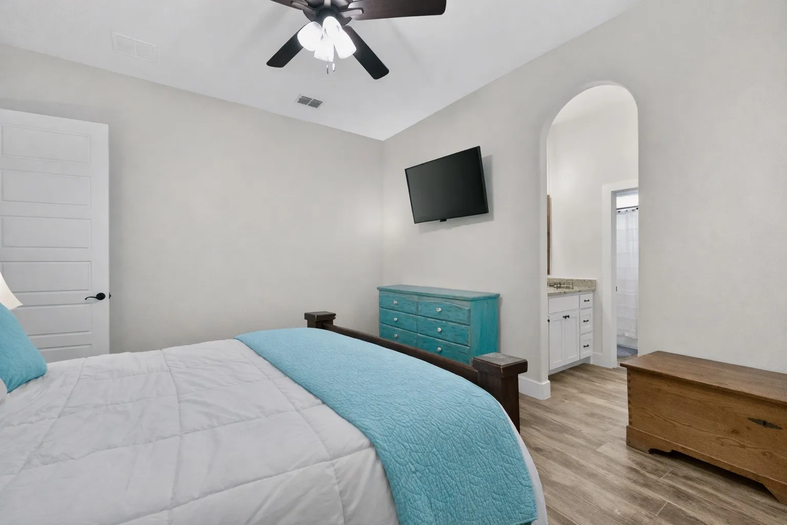 Bedroom featuring wood-finish flooring, a ceiling fan, and a paneled interior door