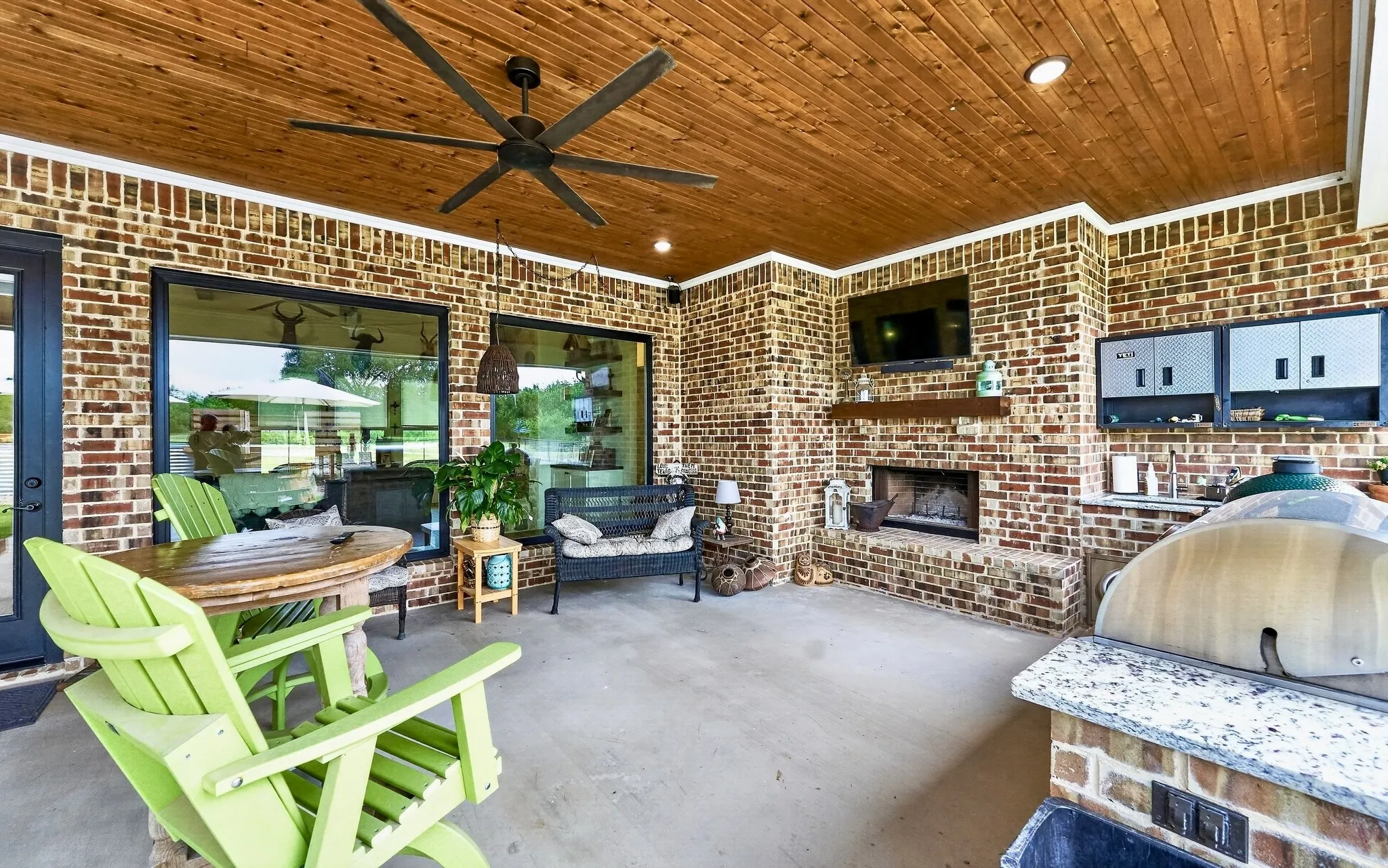 Spacious outdoor living area with a wood-finish plank ceiling, brick walls, and concrete flooring