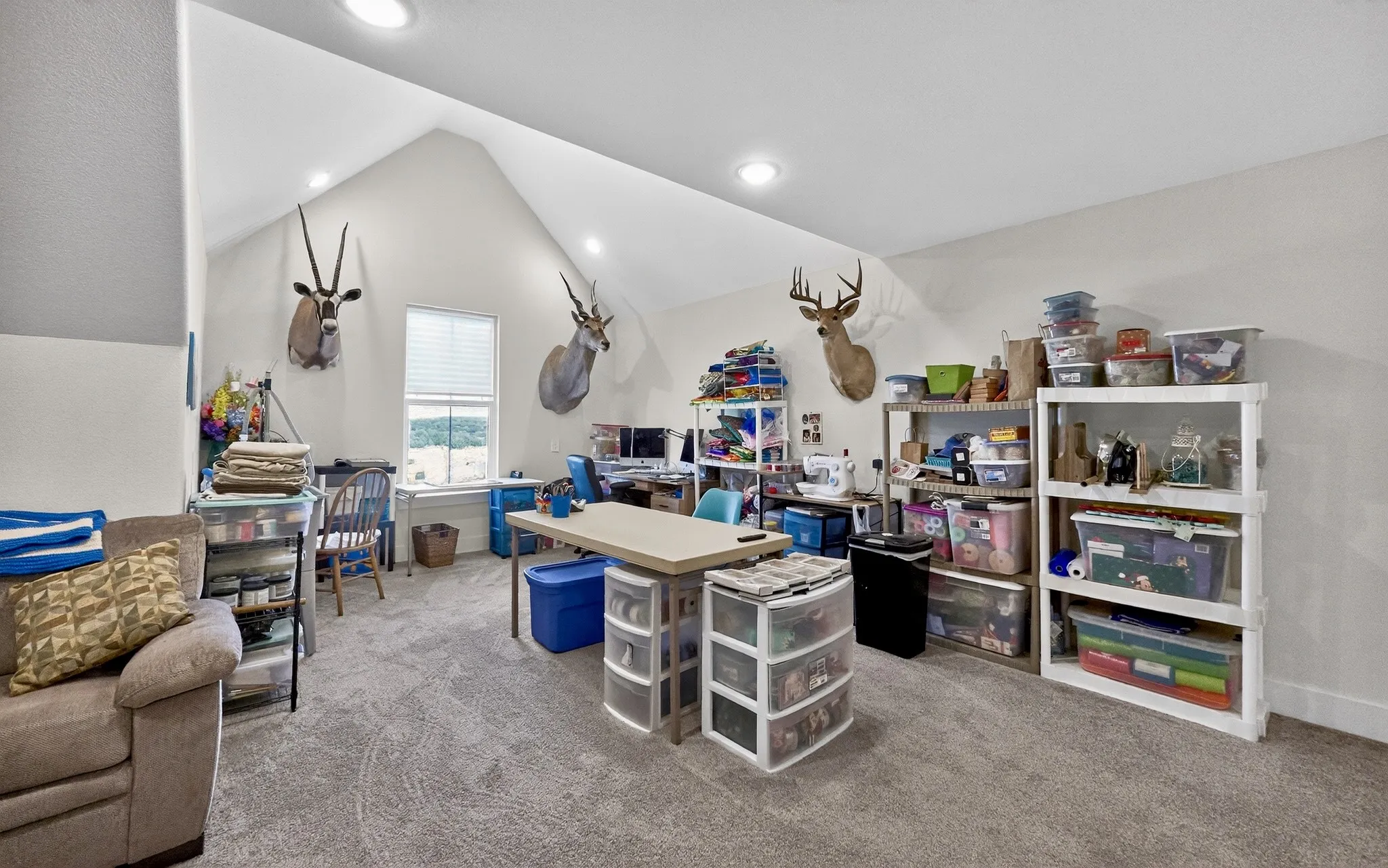 Spacious room featuring vaulted ceilings with recessed lighting, a window with blinds, and light-colored carpeting