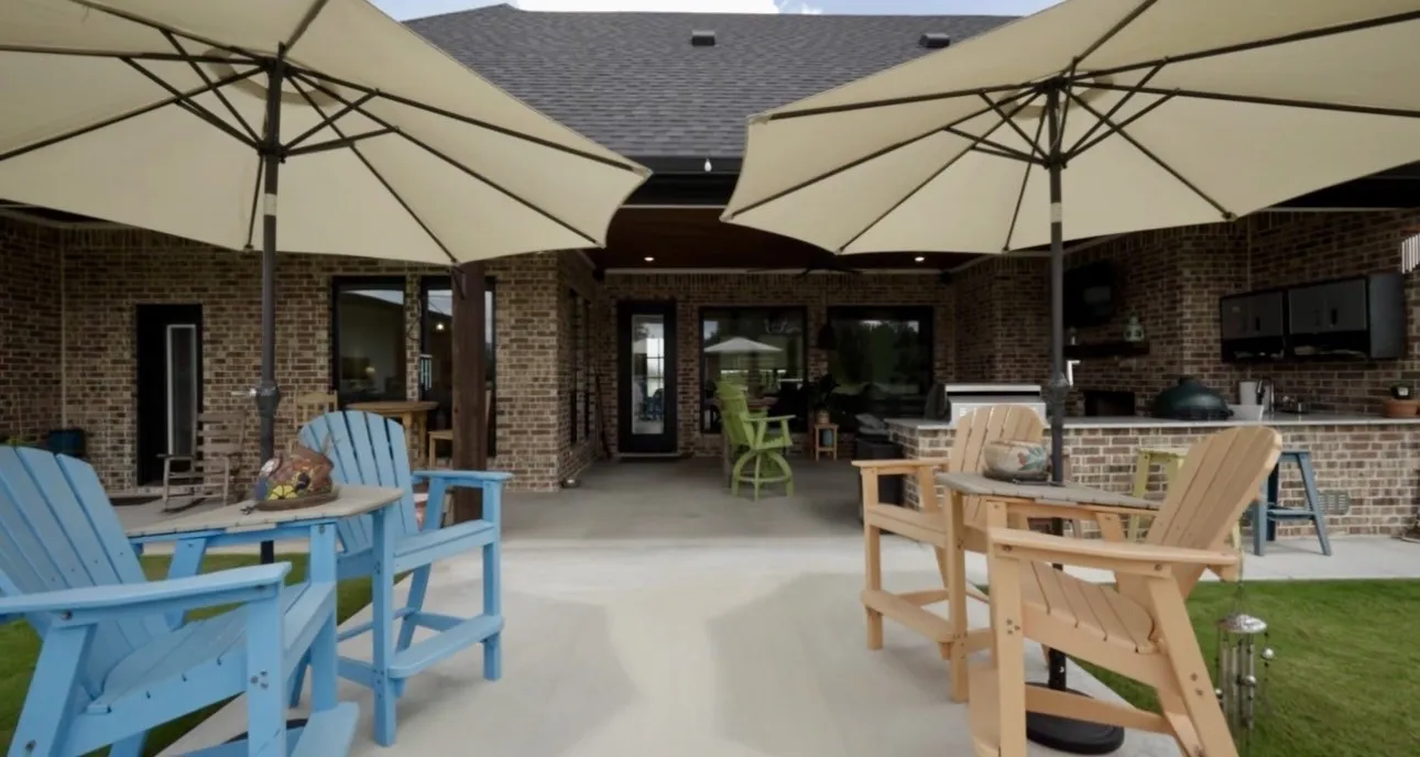 Expansive covered patio featuring a brick exterior, concrete flooring, recessed lighting, and an outdoor kitchen area