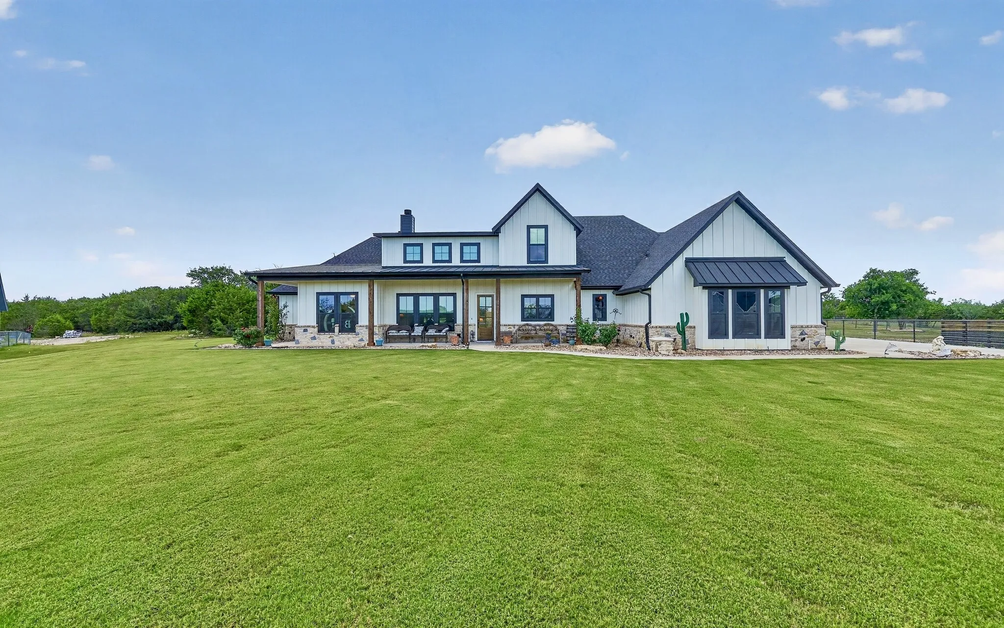 Modern farmhouse exterior featuring white board and batten siding, dark trim, and a black shingle roof