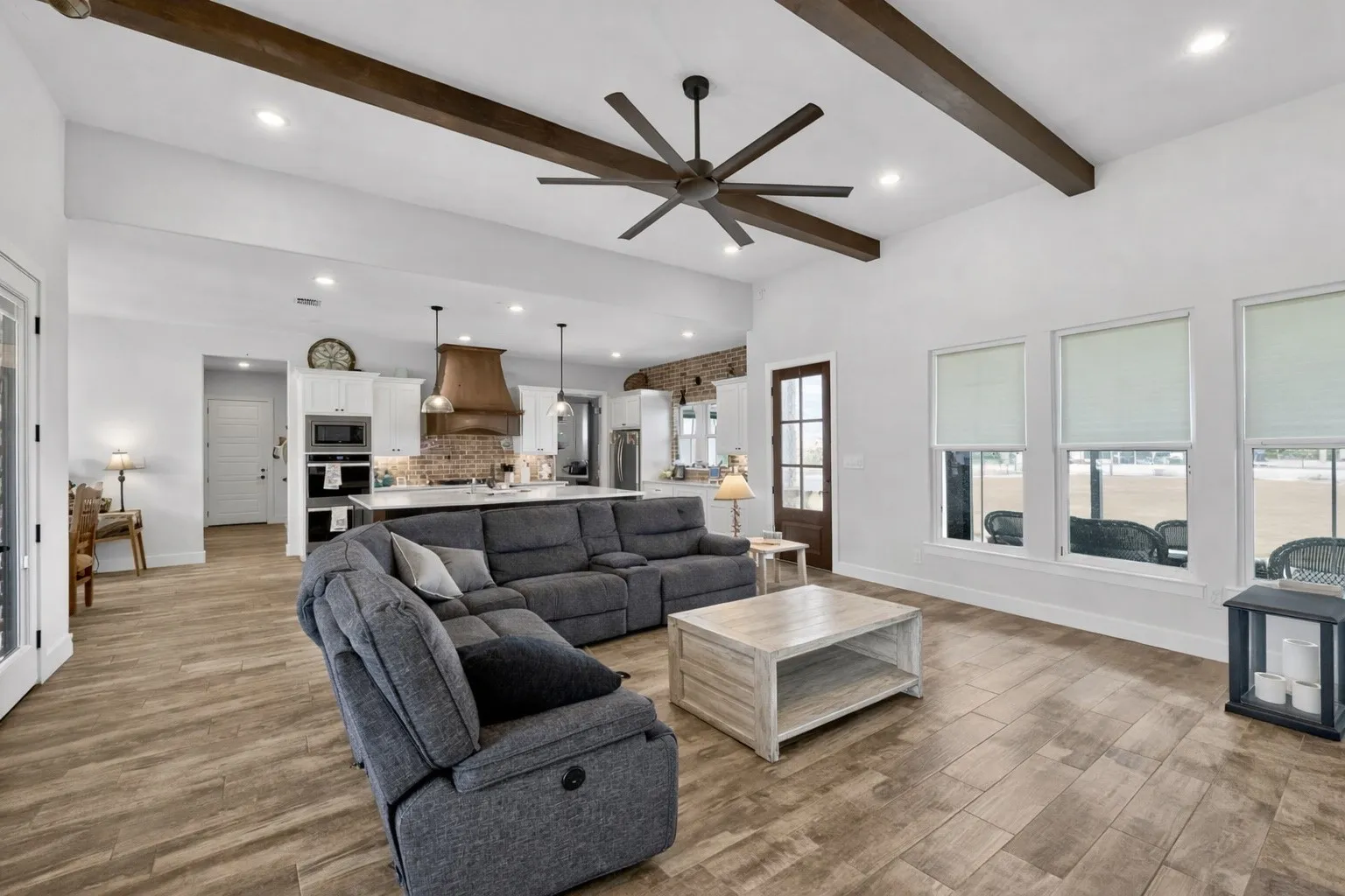 Spacious living area featuring high vaulted ceilings with exposed wood beams, wood-finish flooring, and recessed lighting