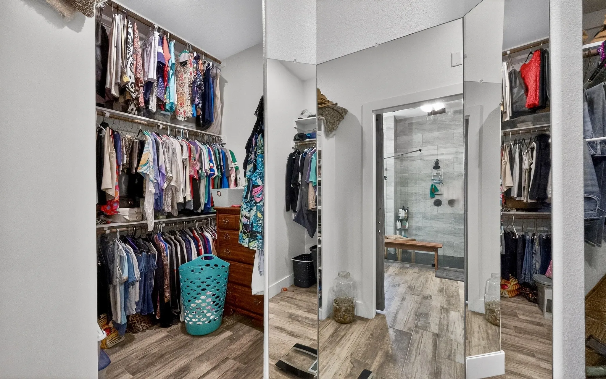 Expansive walk-in closet featuring wood-finish flooring, built-in shelving, and multiple clothing rods