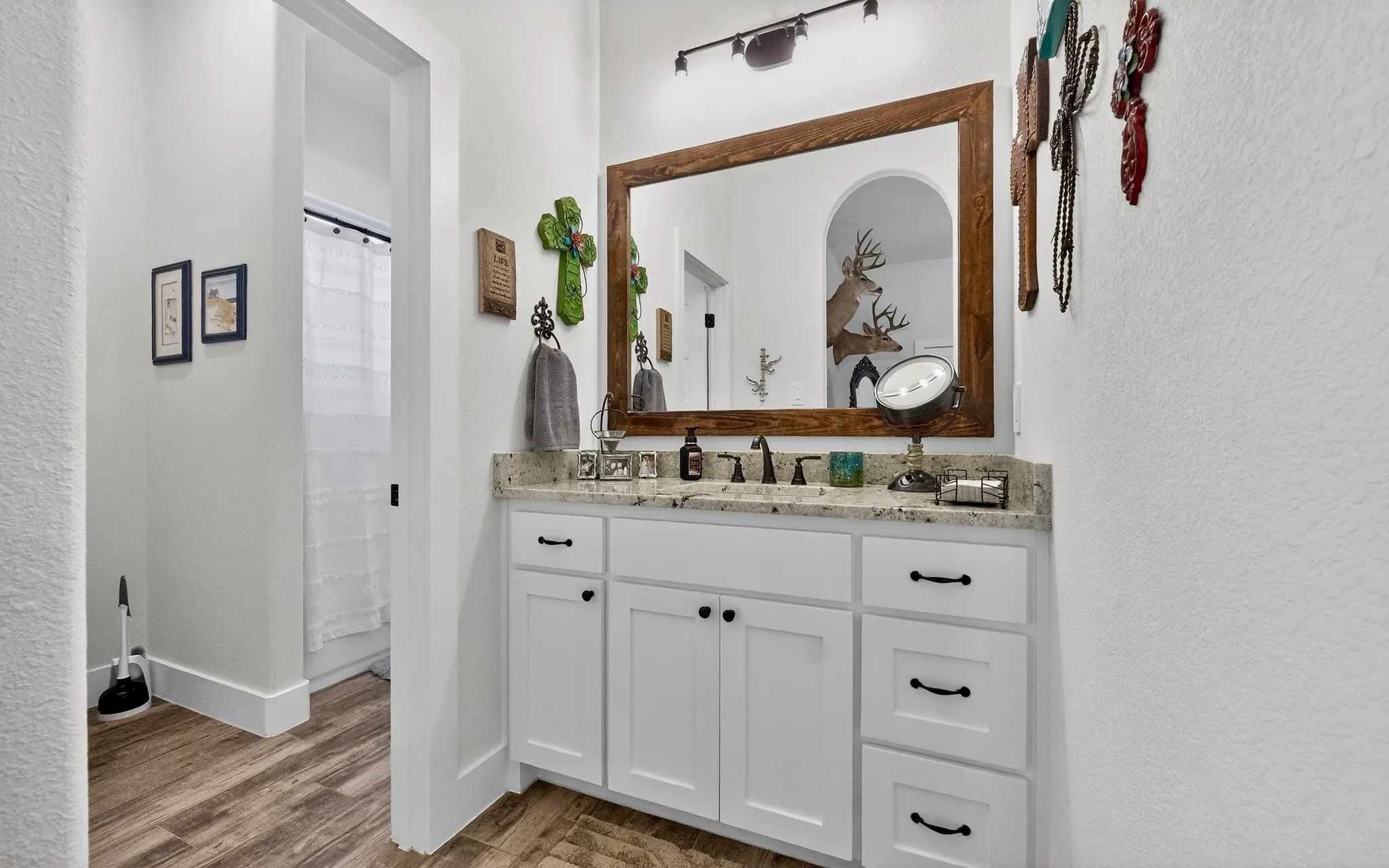 White cabinetry vanity with a light granite countertop and undermount sink
