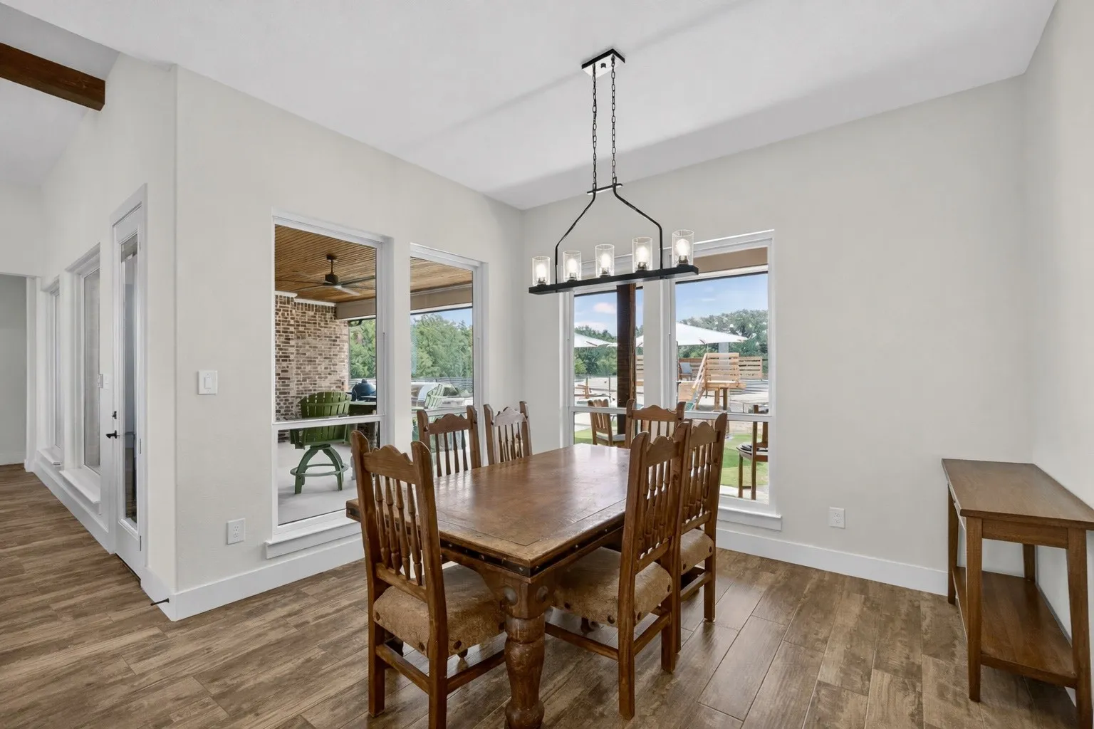 Dining area featuring wood-finish flooring, vaulted ceiling with exposed beam, and a linear chandelier