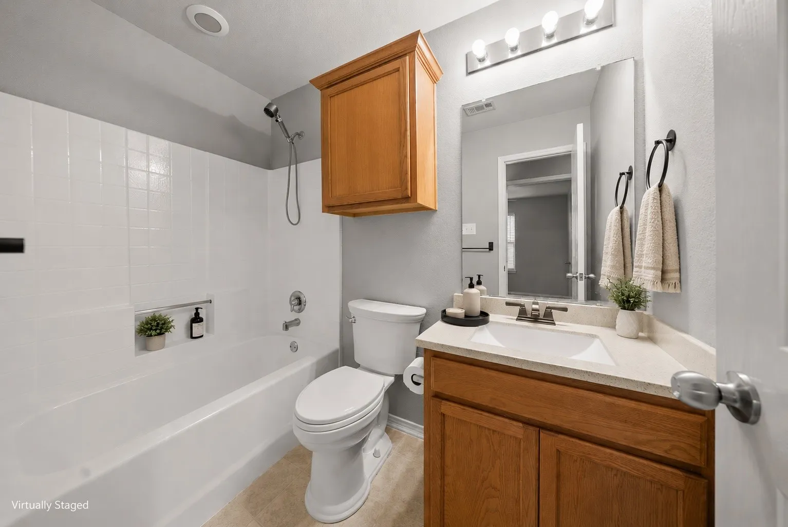 Full bathroom featuring a white tub/shower combination with an integrated niche, a wood-finish vanity with a single sink, a light-toned countertop, and tile flooring