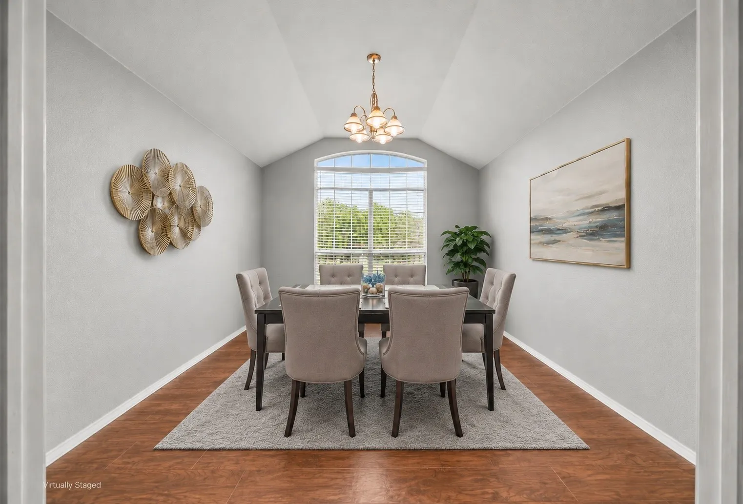 Vaulted ceiling room featuring wood-finish flooring, an arched window with blinds, and a central chandelier
