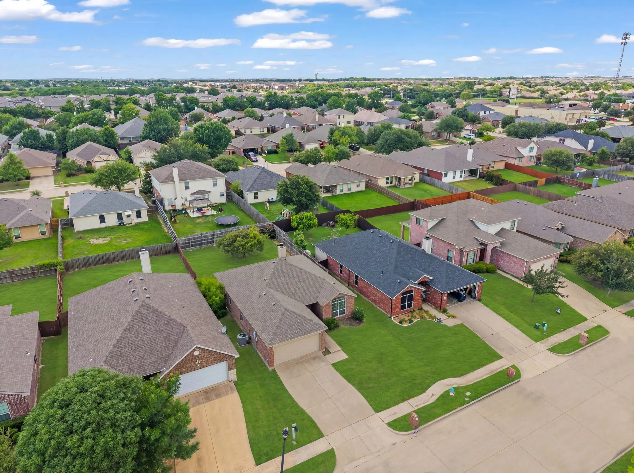 Residential neighborhood featuring a consistent architectural style, mature landscaping, and uniform fencing