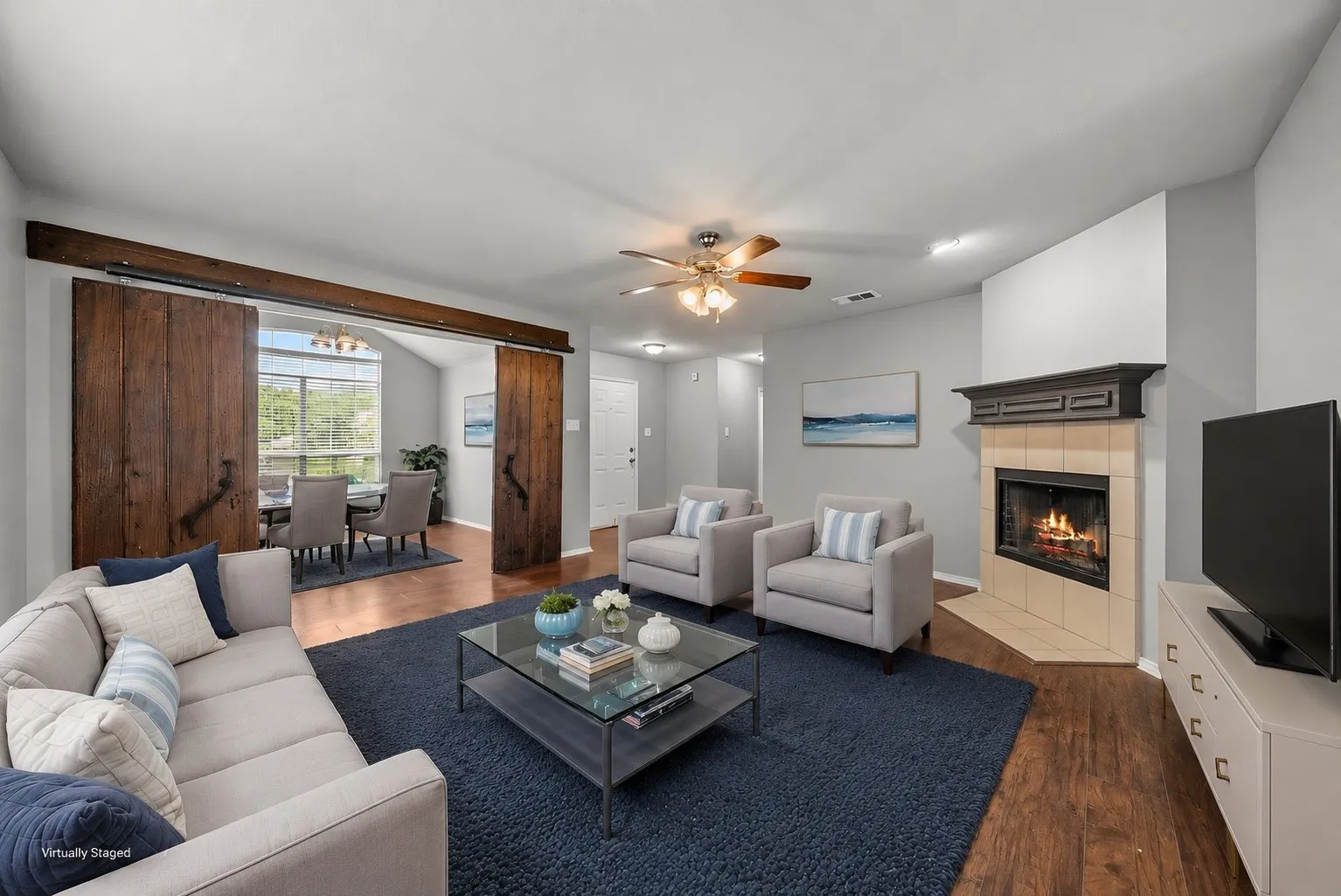 Spacious living area featuring wood-finish flooring and a corner fireplace with a tiled surround