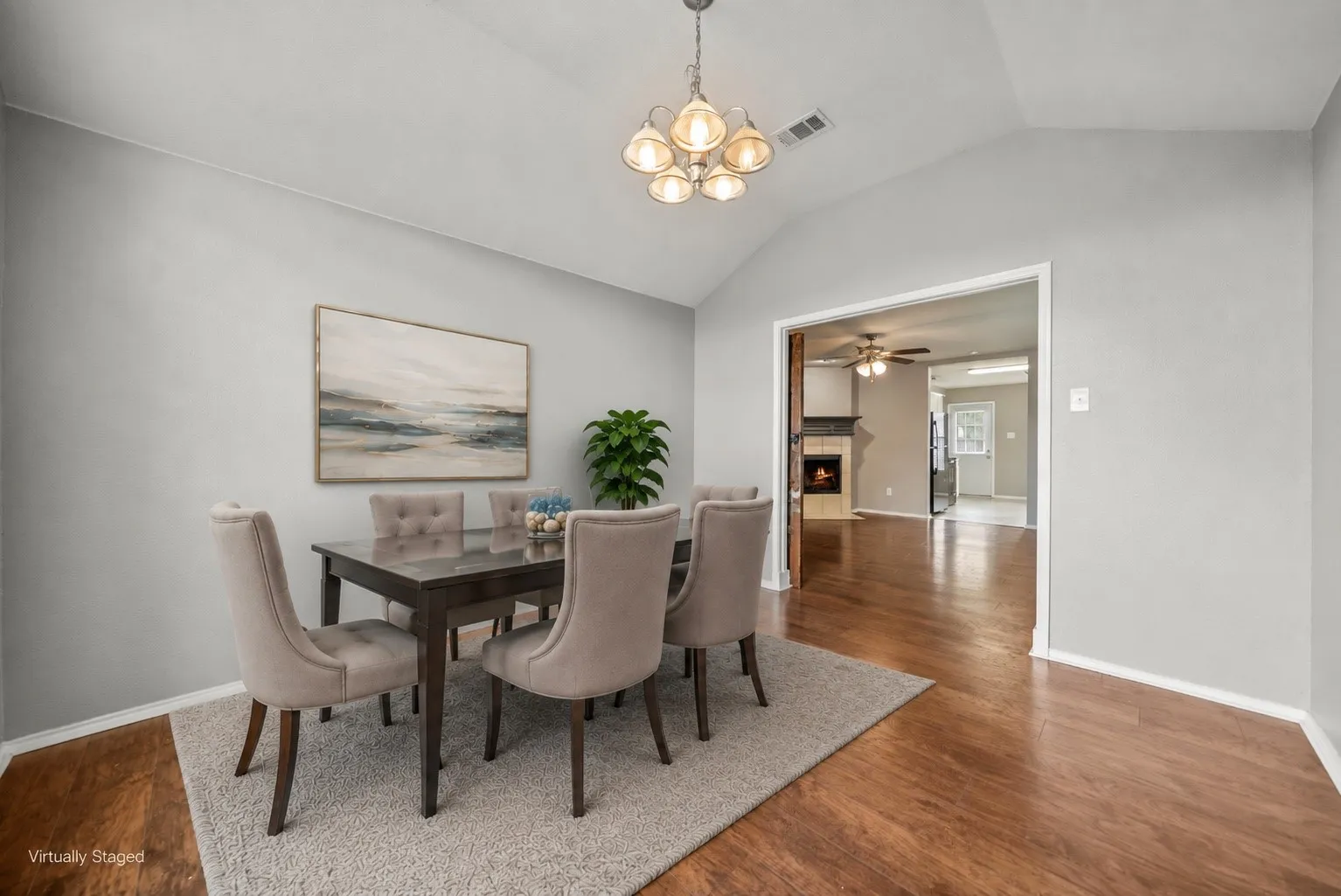Dining area featuring vaulted ceilings, wood-finish flooring, and a decorative chandelier