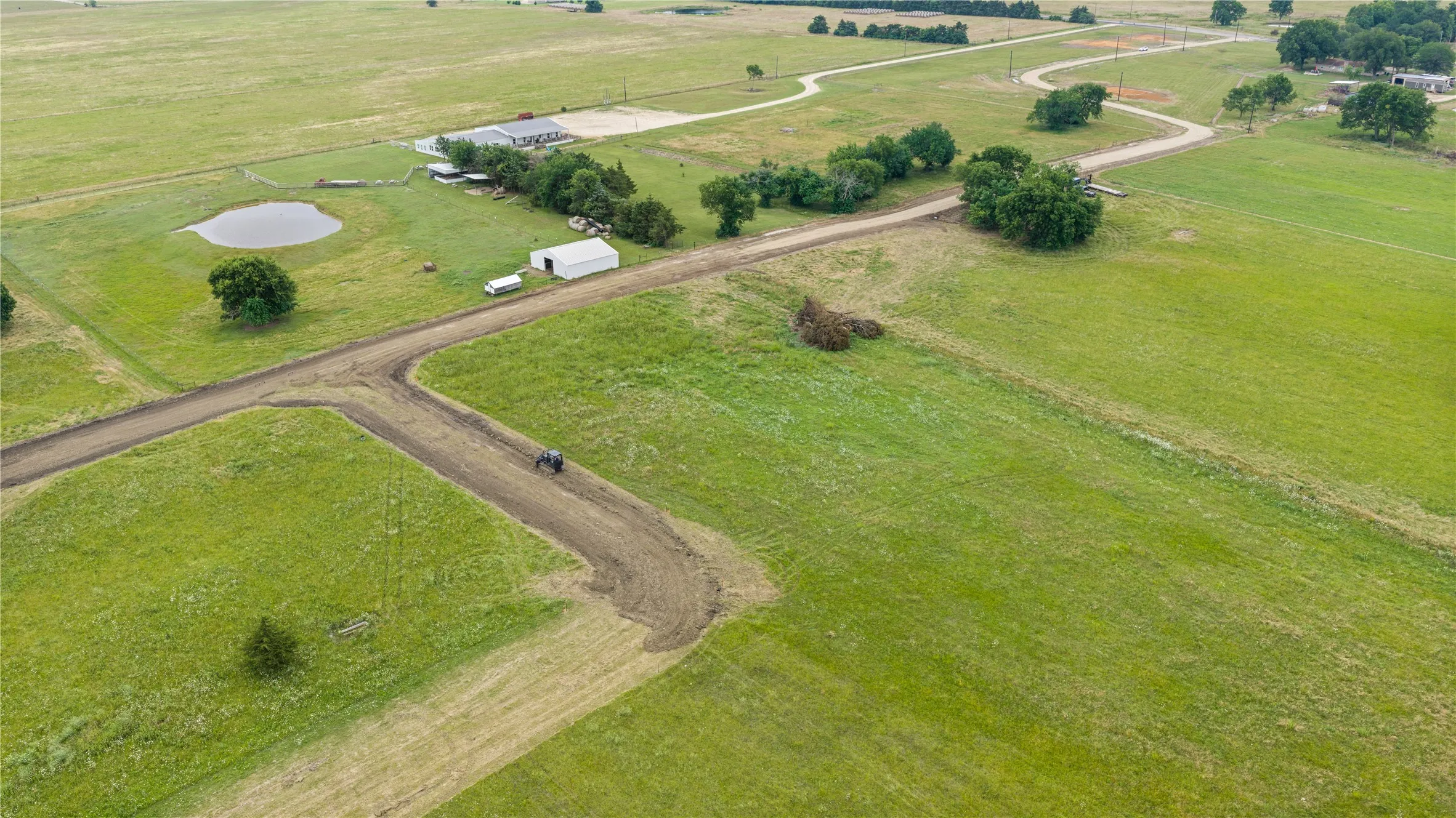 Expansive green pastures featuring a developed dirt road