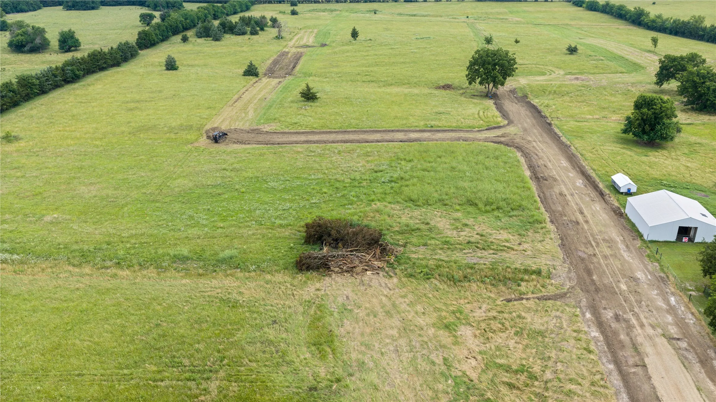 Expansive green landscape with established tree lines and partially cleared pathways