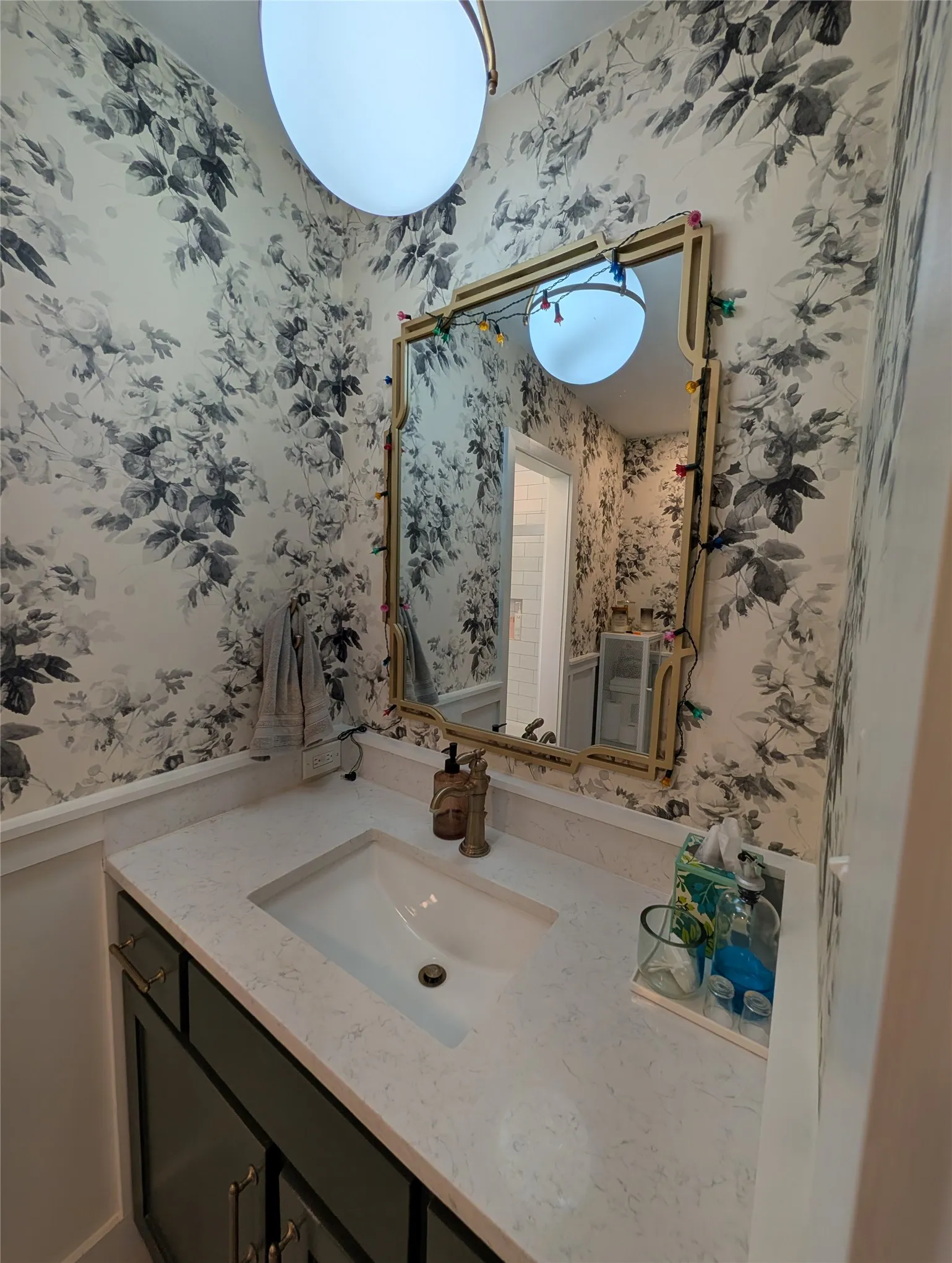 Vanity area featuring botanical wallpaper, a mounted mirror, and a white inset sink